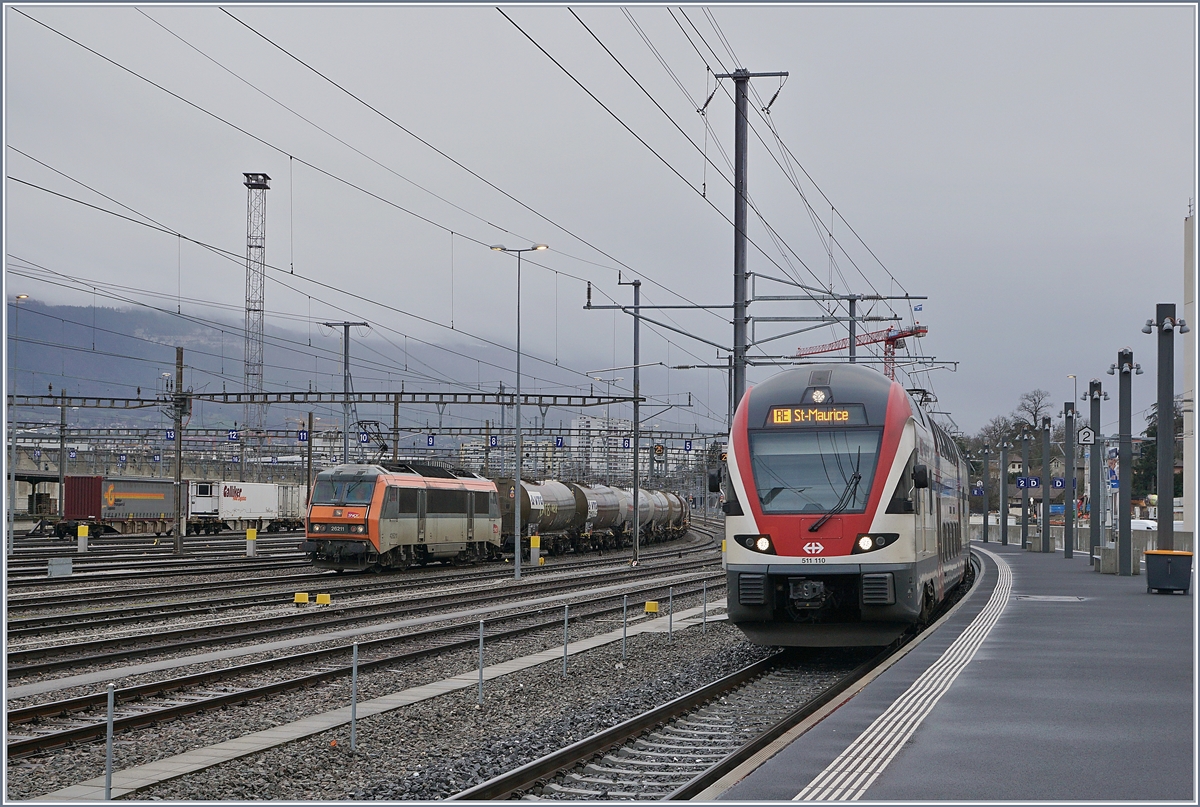 Der SBB RABe 511 110 nach St-Maurice erreicht Lancy Pont Rouge, während im Güter- bzw. Rangierbahnhof Genève La Praille gleich gegenüber die SNCF BB 26211 wartet.

13. Februar 2020