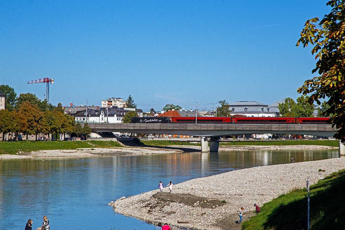 Der Taurus II ÖBB 1116 229–6 (A-ÖBB 91 81 1116 229-6), überquert einen ÖBB Railjet schiebend, am 12.09.2022 die Salzach und erreicht bald den Hauptbahnhof Salzburg.

Die Lok ist komplett schwarz beklebt bis auf weißen Schriftzug  G. Bechtold 22  auf der Seite, es ist ein Kunstprojekt des österreichischen Künstlers Gottfried Bechtold. Was daran Kunst entzieht sich meiner Kenntnis, oder ich bin ein Kunstbanause. 

Die Elektrische Universallokomotive vom Typ Siemens ES64U2  (Taurus II)  wurde 2004 von Siemens im TS Werk Linz unter der Fabriknummer 20950 gebaut und an die ÖBB (Österreichische Bundesbahnen) als 1116 229-4 geliefert. Sie hat die Zulassungen für Österreich, Deutschland und Ungarn.