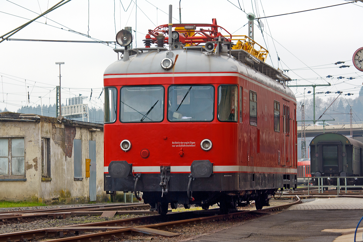 
Der Turmtriebwagen 701 099-4, ex DB 701 099-4, ex Deutsche Bundesbahn -  Kassel 6206, der Lokvermietung Aggerbahn (Andreas Voll e.K., Wiehl) ist am 22.11.2014 beim Südwestfälische Eisenbahnmuseum in Siegen abgestellt. Die Aufnahme entstand vom Gehweg aus, durchs Tor.

Der Turmtriebwagen wurde 1964 bei WMD in Donauwörth unter der Fabriknummer 1512 gebaut.  Bei der DB war er in Kassel, Marburg und Gießen beheimatet. Nach der Ausmusterung kam er zur VEB - Vulkan-Eifel-Bahn in Gerolstein, bis er zur Aggerbahn kam. Die altrote Farbgebung hier entspricht der  ursprünglichen  Farbgebung. 

Die Turmtriebwagen (TVT), der Baureihe 701, auf Basis der Uerdinger VT 98 wurden von 1955 bis 1974 in 13 Bauserien von der DB beschafft. 

Die Regelturmtriebwagen werden zum Bau und zur planmäßigen Untersuchung der elektrischen Fahrleitungen sowie zur Beseitigung von Störungen und Schäden eingesetzt, aber auch für Brücken- und Bauwerkprüfungen.
Der Rohbauwagenkasten besteht aus einer Schweißkonstruktion in Profilbauweise aus Stahl. Für die Sonderausrüstung, die geforderte hohe Zuladung und die heb- und senkbare Arbeitsbühne wurde der Wagenkasten mit einem besonderen Untergestell verstärkt. 

Der Wagengrundriss ist in zwei Führerstände und einen 26 m² großen Werkstattraum aufgeteilt. Die Führerstände sind durch Drehtüren mit dem Werkstattraum verbunden. Die Werkstatt dient insbesondere zum Lagern von Ersatzteilen, Werkzeugen und Arbeitsvorrichtungen, die in Regalen an den Seitenwänden untergebracht sind. Eine Werkbank ermöglicht kleinere Reparaturarbeiten. Außerdem sind ein Schreibtisch, ein Kleiderschrank und ein beheizbarer Kleidertrockenschrank vorhanden. 

Zur Beobachtung der Fahrleitungsanlage während der Fahrt befindet sich im Werkstattraum eine Beobachtungskanzel mit Podest. Zwei Suchscheinwerfer ermöglichen eine Kontrolle der Fahrleitung auch bei Dunkelheit. Auf dem Dach des Regelturmtriebwagens ist ein Stromabnehmer zur Prüfung der Fahrdrahtlage und des Zusammenwirkens von Fahrleitung und Stromabnehmer aufgebaut. Mit einer Verstelleinrichtung kann der Anpressdruck reguliert werden.

Die Arbeitsbühne ist hydraulisch heb und senkbar sowie elektrisch - im Notfall auch manuell - drehbar. Um auch in den Querfeldern der Bahnhöfe jeden Punkt erreichen zu können, ist zusätzlich eine auf 8 m Steighöhe ausziehbare Stahlleiter auf der Arbeitsbühne vorhanden. Mit einer aufsteckbaren Zusatzleiter lassen sich Fahrleitungsbauteile noch in 15 m Höhe über Schienenoberkante erreichen. Die Hub- und Senkbewegungen sowie das Schwenken der Bühne ist von der Arbeitsbühne aus steuerbar. 

Führerstände, Beobachtungskanzel und Arbeitsbühne sind durch eine Lautsprecheranlage verbunden. An das Unterhaltungspersonal außerhalb des Wagens können Anweisungen über schwenkbare Lautsprecher gegeben werden. Für Sprechverbindungen mit Bahnhöfen ist eine Funksprechanlage eingebaut. 

Die Maschinenanlage besteht aus zwei voneinander unabhängigen 6-ZylinderUnterflur-4-Takt-Dieselmotoren, vom Typ Büssing U10, mit Kraftstoff- und Kühlanlage, einer hydraulischen Kupplung, einem Sechs-Ganggetriebe mit elektromagnetischer Schaltung und einem Achswendegetriebe. Die für das Verlegen eines neuen Fahrdrahtes notwendige geringe Dauergeschwindigkeit von 5 km/h wird mit einer kombinierten Drehzahl-Füllungsregelung ermöglicht.

Die Druckluft für Bremse und Nebenverbraucher wird von zwei Luftpressern erzeugt, die von den Fahrmotoren mit angetrieben werden. Als Stromquellen dienen, bei ruhendem Dieselmotor, vier Einzelbatterien, die über 4 x 700 W-Lichtmaschinen aufgeladen werden. Zusätzlich sind die Batterien über eine Ladeeinrichtung aus einem 220 V Ortsnetz aufladbar. Auf der Arbeitsbühne und in der Werkstatt stehen Steckdosen zur Verfügung. 

Die Heizung des Wagens erfolgt über die Motorenwärme. Zwei Ölheizgeräte ermöglichen ein Vorheizen und Warmhalten der Maschinenanlage und heizen den Werkstattraum sowie die Führerstände, wenn der Motor nicht in Betrieb ist und bei extrem tiefen Außentemperaturen.

Technische Daten:
Achsformel: AA
Spurweite:  1.435 mm (Normalspur)
Länge über Puffer:  13.950 mm
Länge des Wagenkastens:  12.750 mm 
Breite des Wagenkastens:   3.000 mm  
Wagenhöhe von SO bis Oberkante Dach: 3.700 mm
Achsstand: 6.000 mm  
Raddurchmesser: 900 mm  
Dienstgewicht: 24,6 t (bei voller Zuladung 29,0 t)
Kleinster befahrbarer Gleisbogen:  125 m  
Motor:  6-Zylinder Unterflur 4-Takt-Dieselmotor, Typ Büssing U10
Motorleistung:  2 x 110 kW (150 PS) bei 1.900 U/min 
Höchstgeschwindigkeit:   90 km/h 
Mindestgeschwindigkeit beim Prüfen: 5 km/h  
Kupplungstyp:  Schraubenkupplung


Daten der Arbeitsbühne:  
Länge der Plattform: 4.550 mm
Breite der Plattform: 1.660 mm
Hubhöhe: 1.000 mm
Hubzeit: 16 sec.
Fußbodenoberkante der Bühne über SO: 4.150 bis 5.150 mm
Schwenkbereich nach beiden Seiten: 90° (elektrischem Antrieb)/100°(Handbetrieb)
Seitliche Verschiebbarkeit der Leiter aus der Mittellage:  je 380 mm
Länge der ausgezogenen Leiter: 8.000 mm (ohne Aufsteckleiter)/10.000 (mit Aufsteckleiter)
Zulässige senkrechte Belastung der Bühne :  300 kg
Gesamtgewicht der zu hebenden Teile:  1.600 kg
Tragkraft der hydraulischen Hubvorrichtung:   3.000 kg
