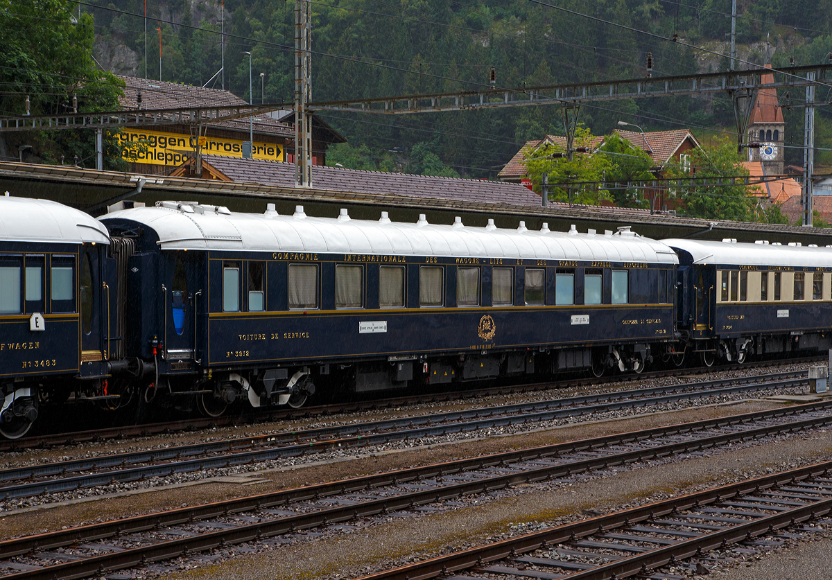 
Der VSOE Servicewagen und Personal-Schlafwagen Nr. 3912 und Personal-Schlafwagen F- VSOE 61 87 06-70 483-9, ex CIWL 51 66 06-41 339-6  (WL 3912) im Zugverbund vom Venice Simplon-Orient-Express am 02.08.2019 beim Halt in Göschenen (CH), leider bei Regen.

Der Servicewagen, ein CIWL Typ YTp Schlafwagen wurde 1949 von der Les Ateliers Metallurgique S. A. in Nivelles (Belgien) gebaut. Ender der 1970er-Jahre wurde er von der VSOE restauriert und zum Servicewagen (mit Personal Schlafabteile und Abstellräume) umgebaut. Zwischen 2003 und 2006 wurden die Wagen nochmals modernisiert und erhielten unter anderem moderne Drehgestelle von Bombardier sowie neue Klimaanlagen. Seitdem sind die Wagen nun für 160 km/h zugelassen.

TECHNISCHE DATEN:
Spurweite: 1.435 mm (Normalspur)
Anzahl der Achsen: 4 in zwei Drehgestellen
Länge über Puffer: 23.450 mm
Drehzapfenabstand: 17.600 mm
Achsabstand im Drehgestell: 2.500 mm
Eigengewicht: 52 t
Höchstgeschwindigkeit: 160 km/h (ursprünglich 140 km/h)
Bettplätze: 14
