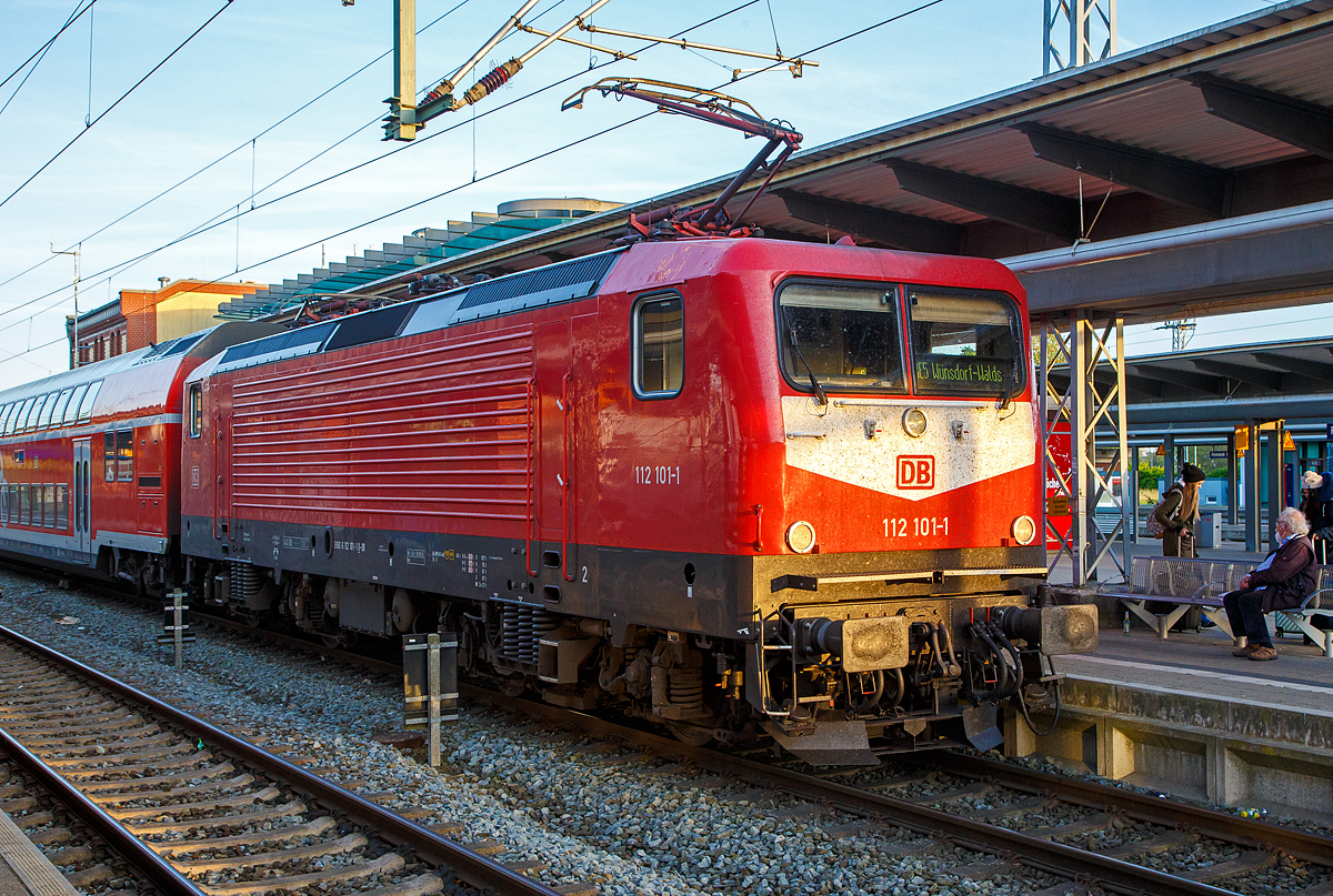 Die 112 101-1 (91 80 6112 101-1 D-DB) der DB Regio Nordost steht am 14.05.2022, mit dem RE 5 (Rostock – Stralsund – Berlin – Wünsdorf-Waldstadt), im Hbf Rostock zur Abfahrt bereit.

Die Lok wurde 1992 von AEG in Hennigsdorf unter der Fabriknummer 21477 gebaut und an die Deutsche Reichsbahn als DR 112 101-1 geliefert. Aus der Hennigsdorfer Lokschmiede LEW - VEB Lokomotivbau Elektrotechnische Werke „Hans Beimler“ Hennigsdorf wurde wieder von der AEG übernommen. DB und DR bestellten jeweils 45 Lokomotiven der Baureihe 112.1. Die an die DR gelieferten Maschinen bekamen die Betriebsnummern 112 101-1 – 112 145-8, die an die DB gelieferten die 112 146-6 – 112 190-4. Nach dem Zusammenschluss der beiden deutschen Bahnen zum 01.01.1994 zur DB AG wurden aus den DR Maschinen DB, so auch die 112 101-1.
