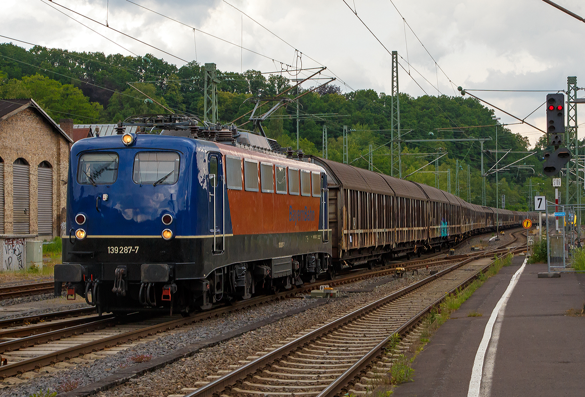 Die 139 287-7 (91 80 6139 287-7 D-BYB) der BayernBahn GmbH fhrt am 09.06.2020, mit dem sogenannten  Henkelzug  (Langenfeld/Rhld. nach Gunzenhausen), durch Betzdorf (Sieg) in Richtung Siegen. 	

Die Lok wurde 1963 von Krauss-Maffei AG in Mnchen-Allach unter der Fabriknummer 18956 gebaut, der elektrische Teil ist von den Siemens-Schuckert-Werke (SSW) in Berlin. Als DB E10 287 wurde in Dienst gesetzt, mit der Einfhrung des EDV-Nummernsystems wurde sie zum 01.01.1968 zur DB 110 287–0. Die Lok ist mit Einholmstromabnehmern ausgerstet, sie ist die letzte gebaute Kasten 110er. Zur 139er wurde sie erst 1994 nach einem Umbau, der Lokkasten wurde auf Drehgestelle der Baureihe 140 (E40) gesetzt und es folgte die Umzeichnung in DB 139 287-7. Zum Mai 2009 erfolgte die Z-Stellung bei der DB AG.

Zum 1.Oktober 2011 wurde die Lok durch die BayernBahn GmbH erworben und erhielt anschlieend eine Untersuchung. Die Neulackierung in kobalt-blau/orange erhielt sie dann 2017.
