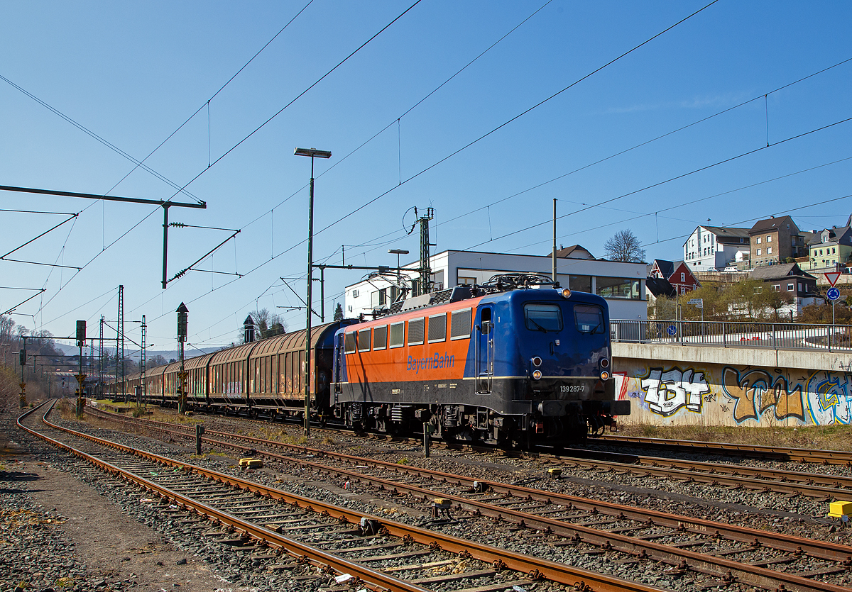 Die 139 287-7 (91 80 6139 287-7 D-BYB) der BayernBahn GmbH fährt am 24.03.2021 mit dem sogenannten  Henkelzug  (Langenfeld/Rhld. nach Gunzenhausen), durch Niederschelden (Sieg) in Richtung Siegen.

Die Lok wurde 1963 von Krauss-Maffei AG in München-Allach unter der Fabriknummer 18956 gebaut, er elektrische Teil ist von den Siemens-Schuckert-Werke (SSW) in Berlin. Als DB E10 287 wurde in Dienst gesetzt, mit der Einführung des EDV-Nummernsystems wurde sie zum 01.01.1968 zur DB 110 287–0. Die Lok ist mit Einholmstromabnehmern ausgerüstet, sie ist die letzte gebaute Kasten 110er. Zur 139er wurde sie erst 1994 nach einem Umbau, der Lokkasten wurde auf Drehgestelle der Baureihe 140 (E40) gesetzt und es folgte die Umzeichnung in DB 139 287-7. Zum Mai 2009 erfolgte die Z-Stellung bei der DB AG.

Zum 1.Oktober 2011 wurde die Lok durch die BayernBahn GmbH erworben und erhielt anschließend eine Untersuchung. Die Neulackierung in kobalt-blau/orange erhielt sie dann 2017.