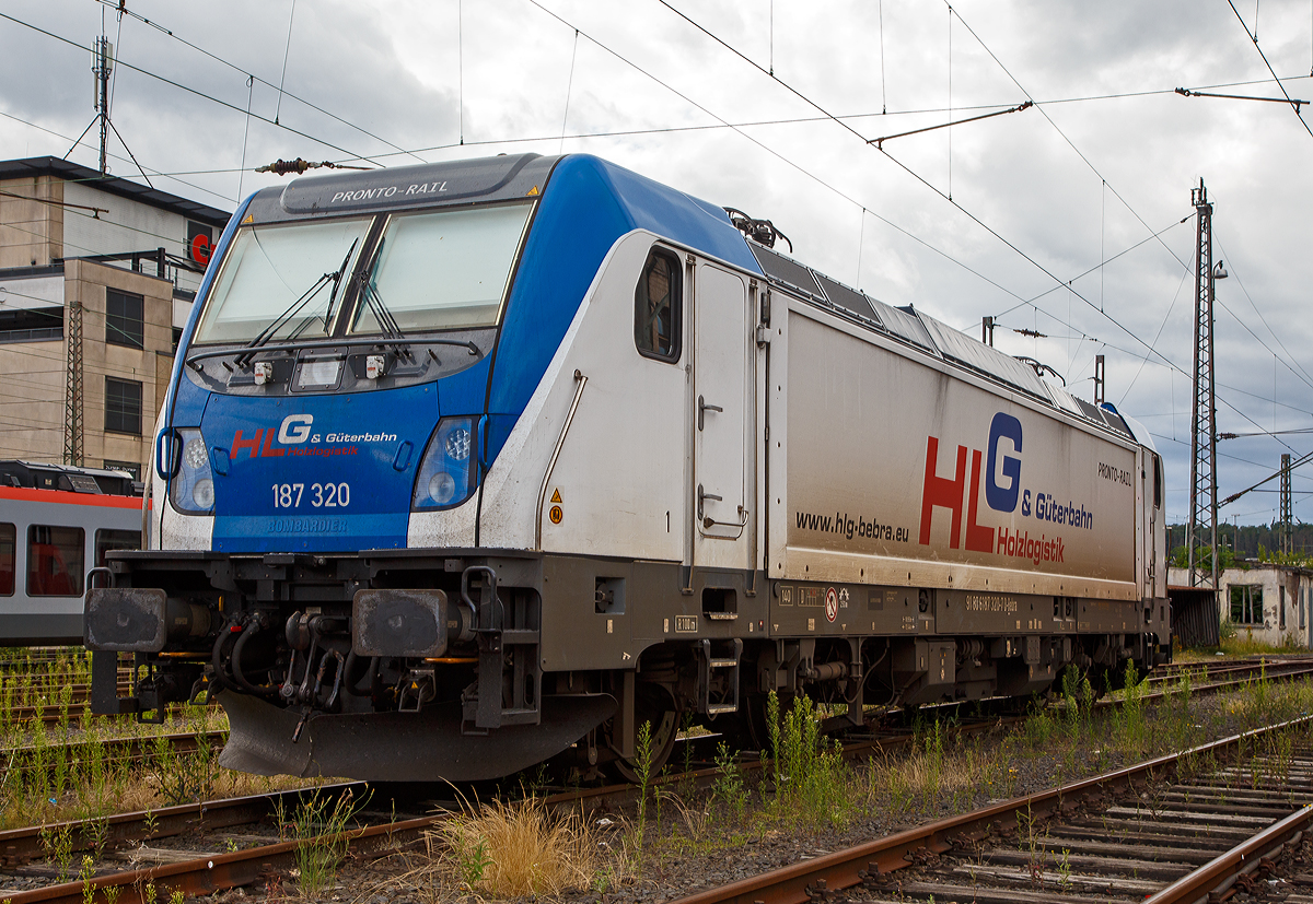 Die 187 320 (91 80 6187 320-7 D-Bebra) der HLG - Holzlogistik und Gterbahn GmbH (Bebra) ist am 31.07.2021 beim Hbf Siegen abgestellt. 

Die Lok Bombardier TRAXX F140 AC3 LM (zugelassen fr 140 km/h daher Variante F140 und nicht F 160). Sie wurde 2018 von Bombardier in Kassel unter der Fabriknummer 35448 gebaut und an die HLG - Holzlogistik und Gterbahn GmbH in Bebra geliefert. Nach meiner Sichtung hat die Lok die Zulassung fr Deutschland (D) und sterreich (A). Fr Ungarn und Rumnien sind die Zulassungen noch nicht erteilt (H und RO sind durchgestrichen).

Wie die Vorgngerinnen AC1 und AC2 ist die AC3 fr den Betrieb unter 15 Kilovolt bei 16,7 Hertz, sowie unter 25 Kilovolt bei 50 Hertz Wechselstrom ausgelegt, und verfgt unverndert ber eine Dauerleistung von 5.600 kW und eine Anfahrzugkraft von 300 kN. Von den Traxx 2E bernommen wurde der Maschinenraum mit Seitengang um das sogenannte Powerpack, bestehend aus Stromrichter und Hochspannungsgerst, womit erstmals alle Varianten dasselbe Layout verwenden.

Neu ist die Kopfform der Traxx-3-Lokomotiven, im Wesentlichen ein auf dem Lokkasten aufgesetztes GFK-Modul. Zudem wurden die Lokomotiven erstmals ab Werk konstruktiv fr den Einbau der Zugbeeinflussung ETCS vorbereitet. Neuerungen betreffen die verfgbaren Drehgestelle: zu den bisherigen Varianten „F140“ mit Tatzlagerantrieb und Zulassung fr maximal 140 km/h, und „P160“ mit Hohlwellenantrieb und Zulassung fr maximal 160 km/h, werden die Traxx-3-Lokomotiven offiziell auch als Variante „F160“ mit Tatzlagerantrieb und Zulassung fr maximal 160 km/h angeboten. Es gibt sie also als TRAXX F140 AC3 und als TRAXX F160 AC3.

Gnzlich neu sind die optional verfgbaren Last-Mile-Module, die es als Last-Mile-Diesel (LMD) mit zustzlicher Last-Mile-Battery (LMB) gibt. Das LMD besteht aus einem Dieselhilfsmotor und einem Kraftstofftank, um auch nicht-elektrifizierte Streckenabschnitte und Anschlussgleise befahren zu knnen. Der Dieselmotor von Deutz verfgt ber einen Hubraum von 7.150 cm, erbringt eine Leistung von 230 kW (180 kW am Rad), mit Batterieuntersttzung 290 kW und erfllt die Stage-IIIB-Abgasnorm. Im Dieselbetrieb werden alle vier Fahrmotoren betrieben, die Anfahrzugkraft betrgt dabei mit Batterieuntersttzung unverndert 300 kN, ohne Batterie 260 kN. Ohne Anhngelast ist damit eine Hchstgeschwindigkeit von 60 km/h mglich, bei 2000 Tonnen Last noch 40 km/h. Der Tankinhalt von 400 Litern reicht fr bis zu acht Stunden Dieselbetrieb, kurze Strecken knnen auch ausschlielich mit der eingebauten Batterie zurckgelegt werden. Der bergang vom elektrischen zum Dieselbetrieb kann whrend der Fahrt erfolgen. Fr den Rangierbetrieb ist zudem eine Funkfernsteuerung erhltlich.

Erstmals wurde der Lokkasten nicht mit glatten Seitenwnden gefertigt, sondern konstruktiv deutlich gnstiger, sind die Seitenwnde der AC3 vertikal gesickt und die Seitenflchen erhielten sogenannte Flex-Panels, eine Vorrichtung zum Einspannen von Planen. Diese wrden die Sicken verdecken, und wren kostengnstiger als Umlackierungen oder Umbeklebungen. Die Nutzung der Flex-Panels wurde jedoch in der Schweiz umgehend untersagt.

TECHNISHE DATEN:
Hersteller:  Bombardier Transportation
Spurweite:  1.435 mm (Normalspur)
Achsanordnung: Bo’ Bo’
Lnge ber Puffer: 18.900 mm
Drehzapfenabstand: 10.440 mm
Achsabstand im Drehgestell: 2.600 mm
Treibraddurchmesser:  1.250 mm (neu) / 1.170 mm (abgenutzt)
Hhe:  4.283 mm
Breite:  2.977 mm
Lichtraumprofil: UIC 505-1
Dienstgewicht:  87 t
Fahrmotoren: 4 Asynchronmotoren
Bremse: Elektrische Bremse (SW-GPR-E mZ)

Daten im Oberleitungsbetrieb:
Hchstgeschwindigkeit: 160 km/h
Dauerleistung: 5.600 kW 
Kurzzeitleistung  Power Boost : 6.000 kW
Anfahrzugkraft: 300 kN
Dauerzugkraft: 252 kN bei 80 km/h
Stromsystem:  15 kV 16,7 Hz~ und 25 kV 50 Hz~

Daten im Dieselbetrieb (Last-Mile):
Nenndrehzahl: 1.800 U/min
Hchstgeschwindigkeit:  60 km/h
Dauerleistung: 230 kW (180 kW am Rad),
Tankinhalt:  400 l