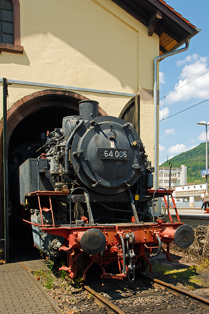 
Die 64 006 (ex DB 064 006-0) schaut aus dem Lokschuppen heraus...
Am30.05.2014 im Eisenbahnmuseum Neustadt an der Weinstraße (Pfalzbahn - Museum). 

Die die Baureihe 64 ist eine Einheits-Personenzugtenderlokomotive der Achsfolge 1'C1' mit niedriger Achslast. Von vorne bis zum Führerhaus hat die BR 64 sehr große Ähnlichkeit mit der BR 24, das kommt aber auch nicht von ungefähr, denn viele Teile des Triebwerkes und der Kessel wurden von der Baureihe 24 übernommen.

Die hier zusehende Lok 64 006 wurde 1928 von der Lokomotivfabrik Borsig in Berlin) unter der Fabriknummer 11962 gebaut und an die DRG geliefert. Nach dem Krieg blieb sie im Westen und kam zu Deutschen Bundesbahn als DB 64 006, in Jahr 1968 erfolgte die Umzeichnung in DB 064 006-0, so war sie bis 1972 im Einsatz und wurde 1973 bei der DB ausgemustert und ging Privateigentum nach Elmstein bis sie 2001 von der DGEG - Deutsche Gesellschaft für Eisenbahngeschichte übernommen wurde.
