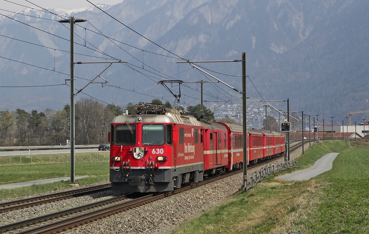 Die am 29.03.2022 aus Chur kommende, bei Felsberg aufgenommene Ge 4/4 630  Trun  wirbt an ihren Seitenwänden für Werbung bei der Rhätischen Bahn