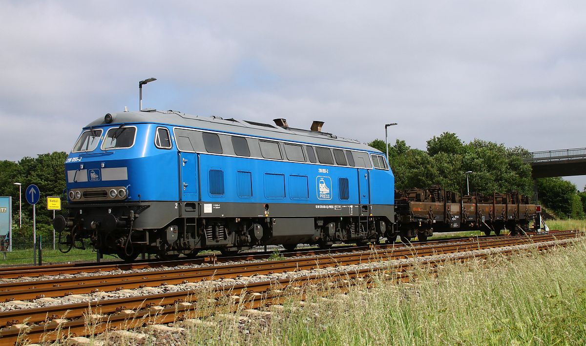 Die blaue PRESS 218 458 (218 055), REV/LS X/ 10.10.19, vor mit Drehgestellen beladenem Niederbordwagen, abgestellt an der Autoverladung Niebüll 02.06.2024 