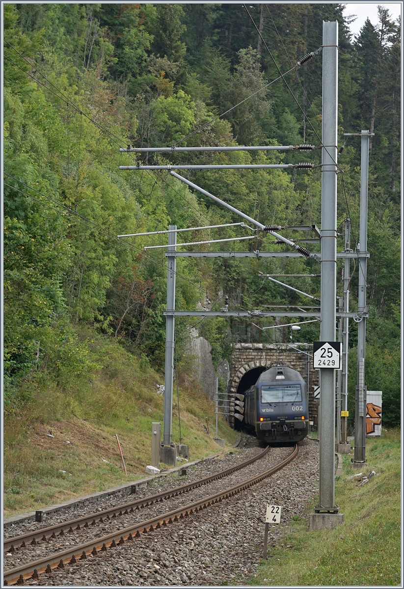 Die BLS Re 465 002 ist mit dem  Kambly-Zug  auf der Fahrt von Bern nach La Chaux de Fonds und taucht in den den 3259 Meter langen Longes Tunnel ein. 

Der Jura ist zwar weit weniger hoch wie die Alpen, doch wie die Neigungstafel am Fahrleitugnsmast im Vordergrund zeigt, sind hier die Steigungen der Gotthard- oder Lötschbergbahn ebenbürdige. 

12. August 2020