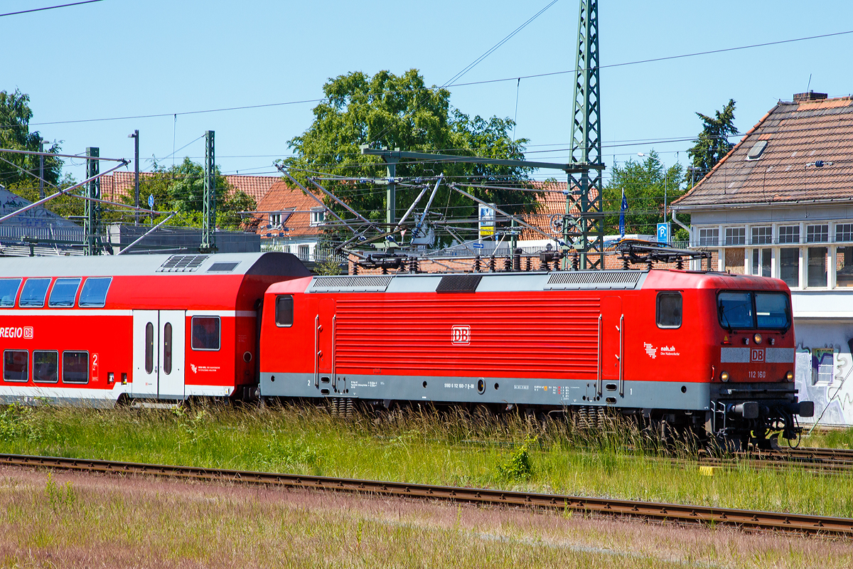 Die DB 112 160 (91 80 6112 160-7 D-DB) der DB Regio Nord erreicht am 11.06.2015 mit einem Regionalzug Lbeck Hauptbahnhof.

Die Lok wurde von AEG in Hennigsdorf (zu DDR Zeiten LEW - VEB Lokomotivbau Elektrotechnische Werke „Hans Beimler“ Hennigsdorf) unter der Fabriknummer 21505 gebaut.

Die 112.1 wurde unverhofft zu einem Symbol fr die Deutsche Einheit, denn sie war die erste Lokomotivbaureihe, die von beiden Bahnverwaltungen gemeinsam beschafft wurde. Man kam berein, dass DR und DB jeweils 45 Loks der leicht verbesserten Loks der DR-Baureihe 112 bei der AEG bestellen wrden (die AEG hatte zwischenzeitlich ihr 1946 enteignetes Werk in Hennigsdorf wieder bernommen). Dies erfolgte hauptschlich aus arbeitsmarktpolitischen Grnden zur Sttzung des Hennigsdorfer Werkes, denn die Bundesbahn htte lieber eine 200 km/h schnelle und universell verwendbare Lok in aktueller Drehstromtechnik nach Art der Baureihe 120 beschafft.

Die uerlich aufflligste nderung ist die Zusammenlegung der groen Spitzen- bzw. Schlusslichter zu kleinen kombinierten Halogenlampen, so wie es bei der alten DB seit jeher gang und gbe ist. 

Entwicklung:
Ab 1976 wurde von der Deutschen Reichsbahn in der DDR die Streckenelektrifizierung auf Grund der lverteuerung wieder forciert, nachdem man zehn Jahre zuvor noch ganz auf Diesellokomotiven gesetzt hatte. Der VEB Lokomotivbau Elektrotechnische Werke „Hans Beimler“ Hennigsdorf (LEW), einziger Hersteller von Elloks in der DDR, bekam den Auftrag, ausgehend von der bewhrten schweren Gterzuglok der Baureihe 250 eine leichtere und technisch modernere vierachsige Variante fr den Personenzug- und mittelschweren Gterzugdienst zu entwickeln. Diese sollte ohne betriebliche Einschrnkungen die Lokomotiven der Baureihe 211 im Schnellzug- und die der Baureihe 242 im Gterzugdienst ersetzen knnen. Die mechanischen Komponenten wurden in Hennigsdorf entwickelt und hergestellt. Die Fahrmotoren kamen vom VEB Sachsenwerk Dresden.

Auf der Leipziger Frhjahrsmesse 1982 wurde der Prototyp 212 001 der ffentlichkeit vorgestellt. Die Lokomotive machte vor allem durch ihr attraktives ueres (wei mit roten Streifen) von sich reden und bekam von den Besuchern den Spitznamen Weie Lady. Nach der Messe begann die DR mit der Erprobung der 140 km/h schnellen Lok, die konstruktiv fr 160 km/h ausgelegt war. Nach der Probezerlegung im Ausbesserungswerk Dessau wurde die Getriebebersetzung gendert und die Maschine am 14. Oktober 1983 in 243 001 umbezeichnet. Durch die genderte bersetzung konnte die Zugkraft deutlich erhht werden, wobei die zulssige Geschwindigkeit auf 120 km/h reduziert wurde.

Serienfertigung DR-Baureihe 243, sptere DB-Baureihe 143
Da zu diesem Zeitpunkt (1984) im DR-Netz kaum mehr als 120 km/h gefahren werden durfte, wurden zunchst Mehrzwecklokomotiven der Reihe 243 beschafft. Von 1984 bis 1990 wurden 640 Loks gebaut.

Die DR-Baureihe 212, sptere DB-Baureihe 112.0
Da man bei der DR bis zuletzt davon ausgegangen war, dass der Ausbau der Transitstrecken nach West-Berlin und deren Elektrifizierung durch die Bundesrepublik finanziert wrde, wurde erst 1991 mit dem Ausbau bestimmter Streckenabschnitte fr mehr als 120 km/h begonnen. Allerdings standen bei der Deutschen Reichsbahn keine entsprechend schnellen Lokomotiven zur Verfgung. Es mussten neue, schnelle Lokomotiven beschafft werden. Man erinnerte sich daran, dass der Prototyp 212 001(spter 243 001) ursprnglich fr 160 km/h ausgelegt worden war. Nach vier Vorserienlokomotiven (212 002 bis 212 005) folgte eine Auslieferung von 35 Serienlokomotiven, bereits als 112 006 bis 040 bezeichnet. 

Von 1992 bis1994 wurden dann 90 verbesserte Loks (je 45 DR und DB) der Baureihe 112.1 von AEG gebaut. Ab Anfang 2001 standen diesie 90 Maschinen (der BR 112.1) aufgrund von Anrissen in der Aufhngung der Schlingerdmpfer fr den hochwertigen Reisezugdienst nicht zur Verfgung. Die zulssige Hchstgeschwindigkeit wurde auf 140 km/h herabgesetzt und alle Schlingerdmpfer untersucht. Darber hinaus wurde die Prfung der Dmpfer im Rahmen der regelmigen Instandhaltung vorgeschrieben. Ende Januar 2001 standen die ersten Maschinen wieder mit einer zulssigen Geschwindigkeit von 160 km/h zur Verfgung.

Die 112.1 fand nach berwindung einiger Kinderkrankheiten ihr Hauptbettigungsfeld in der neu geschaffenen Zuggattung Interregio, aber auch den einen oder anderen InterCity bespannte sie. Durch den Wegfall der Gattung IR und den Ausbau des RE-Netzes mit 140-km/h- und 160-km/h-fhigem Wagenmaterial sind die Lokomotiven heute vorwiegend im Regionalverkehr anzutreffen. Die DB Fernverkehr gab deshalb zum 1. Januar 2004 alle ihre 112.1 an die DB Regio ab. 

DB-Baureihe 114.0
Alle Lokomotiven der Baureihe 112.0 wurden 2000 in die Baureihe 114 umgezeichnet, weil sie fortan zum Bestand von DB Regio gehrten, die Baureihe 112.1 verblieb ja noch beim Fernverkehr. Somit wollte man Verwechslungen zwischen den beiden Serien und damit auch zwischen Nah- und Fernverkehr vermeiden. Als die Fahrzeuge der Baureihe 112.1 auch in den Bestand von DB Regio eingereiht wurden, ist allerdings keine Rckumzeichnung der Baureihe 114 vorgenommen worden. 

TECHNISCHE DATEN der BR 112.1:
Hersteller: 	AEG
Baujahre: 1992 bis 1994 
Ausmusterung: seit 2019
Spurweite: 1.435 mm (Normalspur)
Achsformel: Bo’Bo’
Lnge ber Puffer: 16.640 mm
Drehzapfenabstand: 8.400 mm
Achsabstand im Drehgestell: 3.300 mm
Hhe: 3.980 mm
Breite: 3.120 mm
Dienstgewicht: 82,5 t
Hchstgeschwindigkeit: 160 km/h
Stundenleistung: 4.220 kW
Dauerleistung:  4.000 kW
Anfahrzugkraft:  226 kN
Stromsystem: 15 kV, 16,7 Hz~
Anzahl der Fahrmotoren: 4
Antrieb: LEW-Kegelringfeder
Bremse: KE-Druckluftbremse; elektrische Widerstandsbremse, 2.200 kW Dauerleistung (kurzzeitig bis 2.690 kW belastbar)
Zugbeeinflussung: LZB I 80
