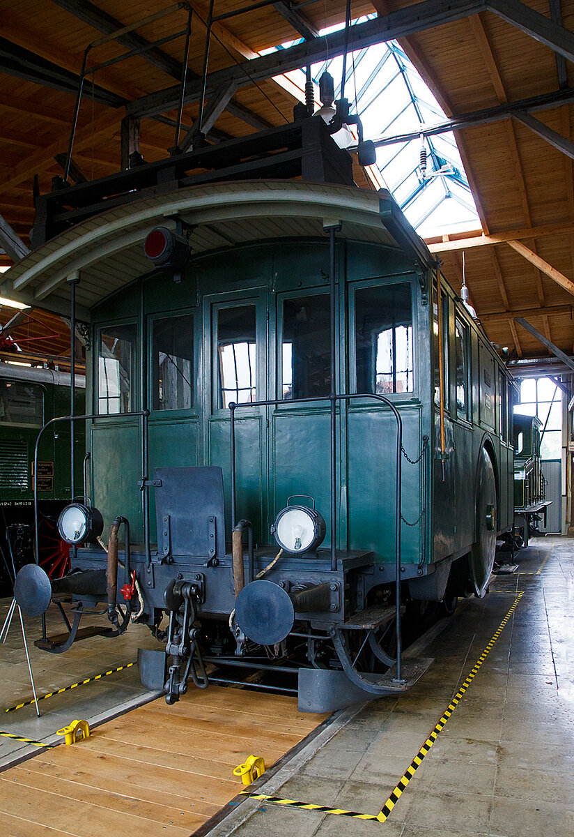 Die Drehstrom- Elektrolokomotive ex BTB De 2/2 Nr.1, ex BTB F 2/2 Nr. 1 (1902 – 1922), ex BTB E2E Nr. 1 (bis 1902), am 11.09.2022 in der Lokwelt Freilassing. Die Lok ist Eigentum des Deutschen Museums - Verkehrszentrum in München und eine Leihgabe die Lokwelt Freilassing

Dem Güterverkehr der Burgdorf-Thun-Bahn (BTB) dienten zwei Lokomotiven vom Typ F 2/2. Bis 1902 wurden sie als E2E bezeichnet, ab 1922 als De 2/2. Diese beiden ersten in der Schweiz, im Jahr 1899, gebauten elektrischen Lokomotiven (De 2/2 Nr.1 und  2) waren eine gemeinsame Konstruktion der Schweizerischen Lokomotiv- und Maschinenfabrik (SLM) in Winterthur für den mechanischen Teil und der Brown, Boveri & Cie. (BBC) für die elektrische Ausrüstung. 

Der noch nicht ausgereifte Einphasen-Wechselstrom-Betrieb konnte zur damaligen Zeit noch nicht eingesetzt werden. Deshalb beschaffte die Schweizer Burgdorf-Thun-Bahn (BTB) zunächst für den reinen Güterzugbetrieb zwei dieser mit Drehstrom (Dreiphasenwechselstrom) angetriebenen Lokomotiven. Das Drehstrom-System konnte nur in einem bestimmten Geschwindigkeitsbereich effektiv arbeiten, so dass ein mechanisches Schaltgetriebe für zwei maximale Geschwindigkeiten notwendig war, nämlich für 18 und 36 km/h.

Ab 1933 wurde der Drehstrombetrieb auf dieser Strecke eingestellt und die beiden Lokomotiven ausgemustert. Die beiden Lokomotiven sind als weltweit erste Drehstromlokomotiven für den Vollbahnbetrieb erhalten geblieben. Die Nr. 1 befindet in der Lokwelt Freilassing, die Nr. 2 befindet sich im Verkehrshaus der Schweiz in Luzern.

Die beiden Motoren wiesen eine Leistung von je 150 PS (110 kW) auf. Das nur im Stillstand umschaltbare Getriebe ermöglichte zwei Geschwindigkeiten, Die eine bis 18 km/h ließ auf der größten Steigung von 25 ‰ eine Anhängelast von 100 Tonnen zu, die andere bis 36 km/h noch die Hälfte. Wobei die zulässige Höchstgeschwindigkeit betrug 50 km/h, so wurde in den späteren Betriebsjahren in Gefällen stromlos gefahren, um diese zu erreichen. Dank der höheren Geschwindigkeit hätten die Lokomotiven nötigenfalls auch im Personenverkehr Verwendung finden können.

Die beiden 19-poligen Triebmotoren sind beidseits auf einer auf einem Hilfsgestell gelagerten gemeinsamen Welle montiert. Über ein Vorgelege wurde das Drehmoment mittels Kuppelstangen auf die beiden Achsen übertragen. Zum Anfahren war ein für beide Motoren gemeinsamer Widerstand vorhanden, der mit dem in jedem Führerstand vorhandenen Kontroller allmählich ausgeschaltet wurde. Beleuchtung, Heizung und Hilfsbetriebe wurden mit einer Spannung von 100 Volt betrieben. Die Lokomotiven weisen an beiden Enden offene Plattformen auf. Die vier Schleifbügel auf dem Dach legten sich selbsttätig beim Wechsel der Fahrtrichtung nach hinten um. Zum Abbügeln mussten die an den Bügeln angebrachten kurzen Zugseile vom Boden aus mit hölzernen Stangen heruntergezogen und in Arretierhaken eingehängt werden.

TECHNISCHE DATEN:
Baujahr: 1899, Ausmusterung1930
Spurweite: 1.435 mm (Normalspur)
Achsfolge: B
Länge über Puffer: 7.800  mm
Achsabstand: 3.140 mm
Treibraddurchmesser:  1.230 mm
Dienstgewicht: 29.600 kg
Höchstgeschwindigkeit: 18 km/h / 36 km/h (stromlos bergab 50 km/h)
Stundenleistung: 300 PS (220 kW)
Stundenzugkraft: 4.400 daN
Stromsystem: 750 V, 40 Hz ∆
Anzahl der Fahrmotoren: 2
Übersetzungsstufen: 2 (für 18 / 36 km/h)

Die Burgdorf-Thun-Bahn (BTB) war eine Eisenbahngesellschaft in der Schweiz. Ihre Strecke von Burgdorf über Konolfingen nach Thun wurde als erste elektrische Vollbahn der Schweiz im Jahr 1899 dem Betrieb übergeben. Heute ist sie Bestandteil der BLS AG