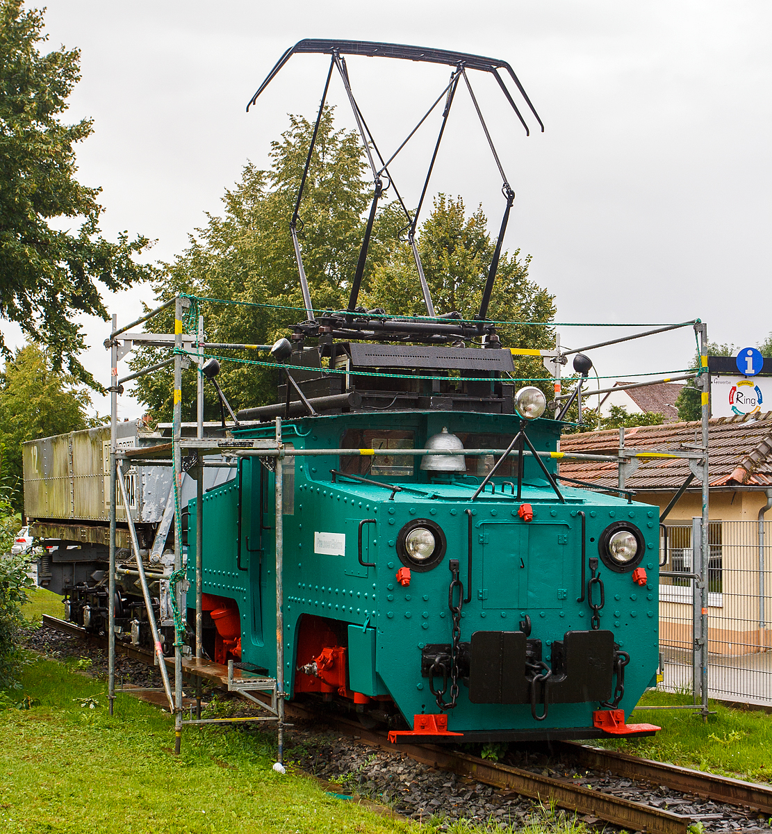 Die ehemalige E-Lok 5 der Preussen Elektra als Denkmal am 18.08.2014 in Wölfersheim-Södel. Leider zum Zeitpunkt der Aufnahme eingerüstet

Die Lok wurde 1924 von Henschel & Sohn in Kassel unter der Fabriknummer 20333 gebaut, die elektrische Ausrüstung ist von SSW. Die Ellok wurde an die Roddergrube AG in Brühl geliefert und als Rodder 1 bezeichnet. Mit der Übernahme durch die Rheinischen Braunkohlenwerke änderte sich die Betriebsnummer in RheinBraun 1055. Im Jahr 1964 erfolgte der Verkauf an die Preussische Elektrizitäts AG in Wölfersheim, wo die Lok nun unter der Nummer 5 bis 1992 für Aschezüge eingesetzt  wurde. Seit 1997 erinnert sie als Denkmal in Wölfersheim an die Bergbautradition.

Markant für diese Henschel E-Loks der Preussen Elektra für die Aschezüge sind die vier am Dach des Führerhauses angebrachten Scheinwerfer, die zur Weichensteuerung dienten.
 
TECHNISCHE DATEN:
Spurweite:  900 mm
Achsformel: Bo
Leistung:  172 kW (2x 86 kW)
Gewicht:  25 t
Höchstgeschwindigkeit: 45 km/h

In der Wetterau wurde bis 1991 Braunkohle, im Tief- und Tagebau abgebaut, ab 1913 wurde die Braunkohle auch zur Stromerzeugung verwendet. Ab den 1954 erfolgte die Stromerzeugung in einem größeren Umfang, so wurde auch die 900 mm Grubenbahn elektrifiziert (1200 V Gleichstrom).  Das Streckennetz wurde jeweils den Erfordernissen (Lage der Gruben) angepasst, die größte Streckenlänge war ca. 23 km.
Mit der Grubenbahn (im Volksmund  Kohlebähnchen  genannt) erfolgte der Transport der abgebauten Braunkohle von den Tagebaubetrieben zum Kraftwerk Wölfersheim einerseits. Aber auch die anfallende Asche im Kraftwerk Wölfersheim (ca. 1000 t pro Tag) musste weg und wurde mit der Grubenbahn vom Kraftwerk zu einem alten Tagebau bei Heuchelheim gefahren und dort abgekippt. 
Der Betreiber war die HEFRAG, später PreussenElektra (eine Tochter der VEBA AG), Konzernnachfolger ist heute die E.ON Energie.

Die Züge und Zugbetrieb
Die Kohlenzüge wurden gezogen von Krupp E-Loks und bestanden aus je sechs Sattelbodenwagen mit 28 bzw. 35 Kubikmetern Inhalt. Die Aschezüge (4 Wagen mit je 16 m³ Inhalt) wurden von (wie diese)  Henschel E-Loks gezogen. Insgesamt waren 35 Kohle- und 21 Aschewagen im Einsatz. Während die Krupp E-Loks 1954-1962 neu an die PREAG geliefert wurden, wurden die 1924 gebauten Henschel E-Loks gebraucht von der Roddergrube der Rheinischen Braunkohlenwerke ab1954 bezogen.

Der Kohlenverkehr lief in den späten Tagebaujahren in aller Regel nur an Vormittagen, während Aschezüge den ganzen Tag über fuhren. Ein Kohlenzug war mit rund 150 Tonnen Kohle beladen. Die Kohle wurde nach dem Entladen auf der Kohlemischhalde mit der Kohle aus anderen Tagebauen gemischt. Von dort wurde die Kohle anfangs über einen Schaufelradbagger, später über ein Haldenaufnahmegerät und Förderbänder zum Kraftwerk transportiert.

Die Weichen im Streckennetz der Grubenbahn wurden übrigens von den Lokomotiven aus über ein Lampensystem geschaltet, welches an jeder Lok angebracht war. Markant war dies vor allem bei den Loks der Aschezüge, da hier die Lampen aufgrund der kleineren Lokomotiven mit vier Auslegern am Führerhausdach angebracht waren.
