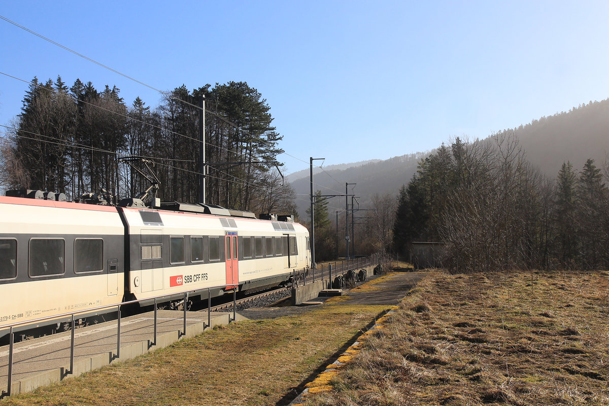 Die Eisenbahn im Vallon de St.Imier (Kanton Bern): Ausfahrt des NPZ Triebwagen 560 232 aus Sonvilier; der Himmel voller Sahara-Sand. 25.Februar 2021