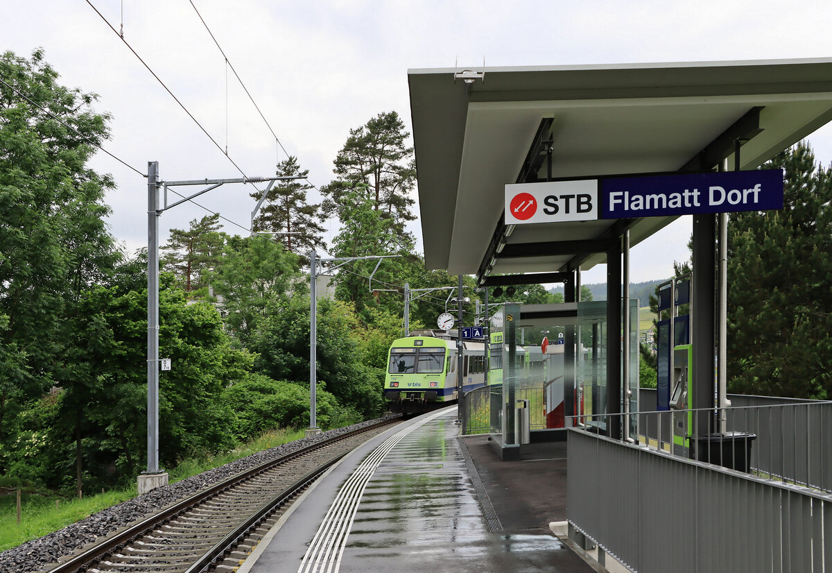 Die kleine Station Flamatt Dorf ist deutlich als  Sensetalbahn  angeschrieben. Triebwagen BLS 722 verschwindet gerade auf die Sensebrücke. 8.Juni 2021 