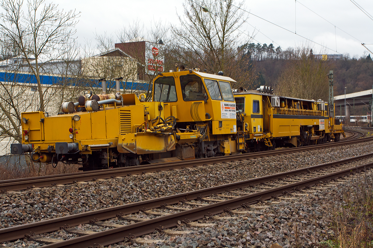 
Die Matisa Schotterplaniermaschine vom Tpy R 20 L (Schweres Nebenfahrzeug Nr. 97 16 38 501 17 – 3) und die Plasser & Theurer Zweischwellenstopfmaschine 09 - 32  CSM (Schweres Nebenfahrzeug Nr. 97 40 68  524 17 -9) beide von der Firma Hans Kaiser GmbH & Co. KG aus Tann stehen am 20.12.2014 auf dem Verbindungsgleis zwischen dem Hbf Siegen und dem KSW Bahnhof Siegen-Eintracht.

Die Schotterplaniermaschine wurde 1993 von MATISA Matriel Industriel S.A in Crissier (Schweiz) unter der Fabriknummer 6714 gebaut und an die Thringer Gleisbau geliefert.

Die modulare Baureihe R 20 wird bereits seit 1987 hergestellt, wir hier ist es Normalspur-Maschine. Entwickelt wurden diese Maschinen jedoch speziell fr Schmalspurnetze oder Netze mit begrenzter Achslast entwickelt. Der Schotterpflug der Baureihe R 20 kann in beide Fahrtrichtungen (Richtungsunabhngig) arbeiten, dies hat den Vorteil Leerfahrten der Maschine zu vermeiden und Schotterverschiebungen von einer Bettungsschulter zur anderen in einem einzigen Arbeitsdurchgang durchzufhren. Daraus ergibt sich ein bemerkenswerter Zeitgewinn, wobei meist das Stopfen den grten Zeitaufwand bentigt. Die groe Beweglichkeit der Seitenpflge ermglicht auch bei hohen Geschwindigkeiten das Umgehen von Hindernissen. Die Anpassung an alle Gleisschulterprofile und das Arbeiten im Seitenbereich der Gleise erfolgt ohne Verletzung des Lichtraumprofils des Nachbargleises.

Die vor der Kabine angeordneten Zentralpflge bleiben stets im Sichtbereich des Bedieners. Alle Maschinen sind mit einem doppelten Bedienungspult ausgerstet. Die reichlich dimensionierte Kabine bietet eine ausgezeichnete Sicht auf den Arbeitsbereich und das Gleis.

Die Brsteneinheit ist mit einem Aufnahmekasten ausgerstet, der den wegschleudernden Schotter aufnimmt und auf ein Frderband leitet, das ihn entweder seitlich auf die Gleisschultern wirft (Version L) oder in einen Silo befrdert (Version LS und LT). 

Technische Daten der  Schotterplaniermaschine R 20 L:
Spurweite: 1.435 mm  (lieferbar 1.000 bis 1.676 mm)
Achsanzahl: 2
Achsabstand: 6.200 mm
Lnge ber Puffer: 13.690 mm
Eigengewicht: 28,5 t
Anhngelast: 20 t
Zur Mitfahrt zugel. Personen: 2
Hchstgeschwindigkeit: 90 km/h
Max. Geschwindigkeit beim Planieren: 12 km/h
Max. Geschwindigkeit beim Kehren: 3 km/h      
Kleinster befahrbarer Kurvenradius:  R 75 m      
Motor:  DEUTZ-Dieselmotor vom Typ F 10 L 413 F      
Motorleistung:  196 kW / 2300 U/min

Beschreibung der P&T Zweischwellenstopfmaschine 09 – 32 CSM siehe: http://hellertal.startbilder.de/bild/Deutschland~Bahndienstfahrzeuge~Schotterplaniermaschinen/392853/die-plasser--theurer-zweischwellenstopfmaschine-09.html