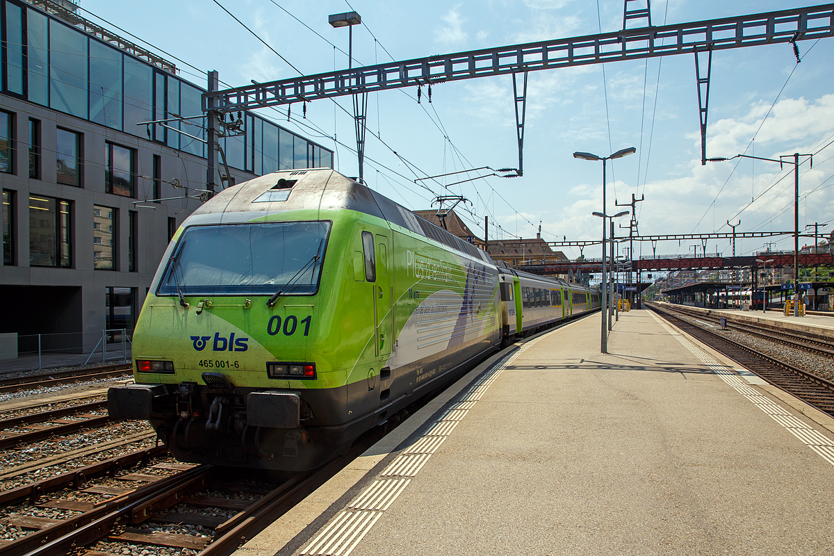 Die Re 465 001-6  Simplon/Sempione  (91 85 4465 001-6 CH-BLS) mit Werbung  Plus d´enTrain – 10 ans – Tunnel de base du Lötschberg“  bzw. in Deutsch auch auf der anderen Lokseite  Mehr DurchZug - 10 Jahre Lötschberg-Basistunnel  fährt am 18.05.2018, als Schublok mit einem BLS EWIII -  Pendelzug in den Bahnhof Neuchâtel ein. 