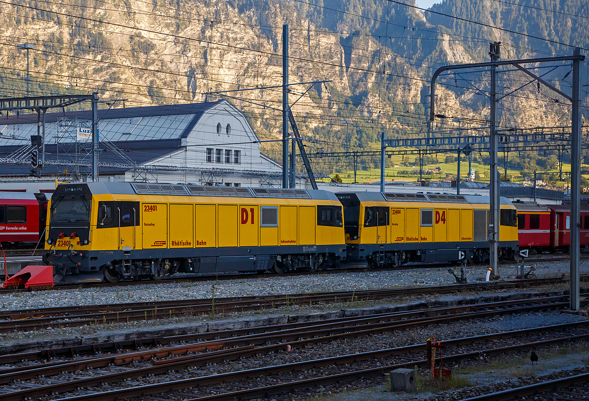 Die RhB Gmf 4/4 23401 „Surselva“ (D1), ex Gmf 4/4 28701, gekuppelt mit der RhB Gmf 4/4 23404 „Bernina“ (D4), ex Gmf 4/4 28704, vierachsige dieselelektrische Universallokomotiven der RhB Infrastruktur, sind am 05.09.2021 beim Bahnhof Landquart abgestellt. Aufgenommen aus dem Zug heraus. 

Vier dieser vierachsigen meterspurigen dieselelektrischen Loks wurde 2013 von Schalker Eisenhütte Maschinenfabrik GmbH in Gelsenkirchen  unter den Fabriknummern 2585 bis 2588 als Gmf 4/4 28 701 bis 28 704 für die RhB gebaut, 2015 wurde sie in Gmf 4/4 23401 bis 23404 um bezeichnet.

Die vierachsige dieselelektrische Lokomotive Gmf 4/4 II (234..) ist eine besondere Entwicklung von Schalke für den Bereich „Infrastruktur“ der Rhätischen Bahn (RhB) in der Schweiz. 

Um im gesamten RhB-Netz einschließlich der Berninabahn eingesetzt werden zu können, zählten zu den Voraussetzungen die Lauffähigkeit in Bögen ab 45 m Radius und Neigungen bis 70 ‰, die Einhaltung einer maximalen Radsatzlast von 16 t, sowie ein kleines Lichtraumprofil (Tunnelprofil). Außerdem ist die Lokomotive auch unter extremen klimatischen Bedingungen zuverlässig einsatzfähig, ihr Einsatzbereich reicht von -35°C bis +40°C, auch bei feinkristallinem Schnee ist sie fahrbereit.
Die Umsetzung dieser technischen Herausforderungen wurde vereint mit der Integration einer Vielzahl spezifischer Komponenten. So verfügt die Lokomotive unter anderem über vier verschiedene Bremssysteme, eine Mehrtraktionsfähigkeit von bis zu drei Lokomotiven, zudem sind sie mit Funkfernsteuerung ausgerüstet. Die Höchstgeschwindigkeit beträgt 100 km/h, die Lokomotiven können jedoch auch bei niedrigen Dauergeschwindigkeiten mit Schneepflügen oder Gleisbauzügen eingesetzt werden. Auch die offizielle Betriebsbewilligung des Schweizer Bundesamts für Verkehr (BAV) macht sie auf dem Markt für Diesellokomotiven einzigartig.

Ihr Haupteinsatzzweck ist der Transport von schweren Bau- oder Spezialzügen auch bei abgeschaltetem Fahrdraht, der Betrieb von Schneefräsen im Winter, das Abschleppen von havarierten Zügen und das Rangieren in den Bahnmeisterbezirken.

Der Lokkasten wurde bei der FTD Fahrzeugtechnik Bahnen Dessau in Stahlleichtbauweise geschweißt mit angeklebten GFK-Fronten und Seitenwänden aus Aluminiumwabenplatten. 

Mit der Entwicklung der Drehgestelle beauftragte die Schalker Eisenhütte Maschinenfabrik GmbH das schweizerische Ingenieurbüro PROSE in Winterthur. Aufgrund der geringen Stückzahl von nur vier Lokomotiven wurde auf die Entwicklung spezieller Fahrmotoren verzichtet, zum Einsatz kommen Antriebe aus dem Asiarunner von Siemens Rail Systems. Die Aufhängung der Motoren erfolgt mittels Tatzlager-Antrieb.

Die Primärfederung erfolgt über Lemniskatenlenker, die somit robuste Konstruktion berücksichtigt die harten Einsatzbedingungen, auf radiale Einstellbarkeit wird verzichtet.

Besonders hohe Sekundärfedern mit speziellen Gummi-Kipp-Elementen tragen den anspruchsvollen Einsatzbedingungen mit sehr kleinen Kurvenradien Rechnung. Daraus resultiert ein geringer Ausdrehwiderstand auch in engen Bögen (kleinster befahrbarer Bogen: 42m). Für stabiles Fahrverhalten bei hohen Geschwindigkeiten auf der Geraden sind bei dem geringen Ausdrehwiderstand Schlingerdämpfer nötig. Von den Sekundärfedern gibt es je Drehgestell 4 Paare, wobei ein Paar aus innerer und äußerer Feder besteht. Die Zugkraft wird drehzapfenlos über Zug-/Druck-Stange an den Lokkasten übertragen. Besonders ist hierbei die doppelte Kröpfung. Nötig ist diese um trotz der großen Auslenkungen ausreichend Abstand zu anderen Bauteilen des Drehgestells zu halten.

Als Besonderheit ist die Materialwahl zu sehen: Um dem angestrebten Winterdienst Rechnung zu tragen ist ein Stahl mit hoher Duktilität bei niedrigen Temperaturen gewählt worden.

Neben dem MTU-Motor ist ein 37 Kilowatt-Hilfsdiesel mit Generator installiert. Bei stehender Lok sorgt er für die Bordstromversorgung bei abgeschaltetem Hauptdiesel sowie die Versorgung von externen elektrischen Anlagen oder Arbeitsgeräten an Baustellen.

Der Auftragswert für die vier dieselelektrische Universallokomotive Gmf 4/4 betrug rund 25 Millionen Franken.

Technische Daten der Gmf 4/4 :
Hersteller: Schalker Eisenhütte Maschinenfabrik GmbH
Hersteller Typenbezeichnung: RDE1800-D064-1000-2586/2013-CH
Anzahl: 4
Baujahr: 2013
Spurweite:  1.000 mm
Achsanordnung:  Bo’Bo’
Länge über Puffer:  16.690 mm
Drehzapfenabstand (theoretisch): 9.800 mm
Radsatzstand im Drehgestell: 2.300 mm
Breite:  2.650 mm
Höhe:  3.885 mm
Treibraddurchmesser: 1.070 mm (neu)
Motor:  V 12-Zylinder-Dieselmotor  vom Typ MTU 12V 4000 R43L (Stage III b)
Antrieb: dieselelektrisch
Antriebsstrang:  Wechselstromtechnik (AC)
Gewicht:  64 t
Leistung:  1.800 kW
Max. Geschwindigkeit: 100 km/h
Tankinhalt: 2.500 l
Max. Anfahrtszugkraft: 230 kN
Dauerzugkraft: 160 kN
Kleinster bef. Halbmesser: 40 m
Max. Anhängelast (Doppeltraktion) bei 70‰: 140 t
Max. Anhängelast (Doppeltraktion) bei 25‰:  420 t
