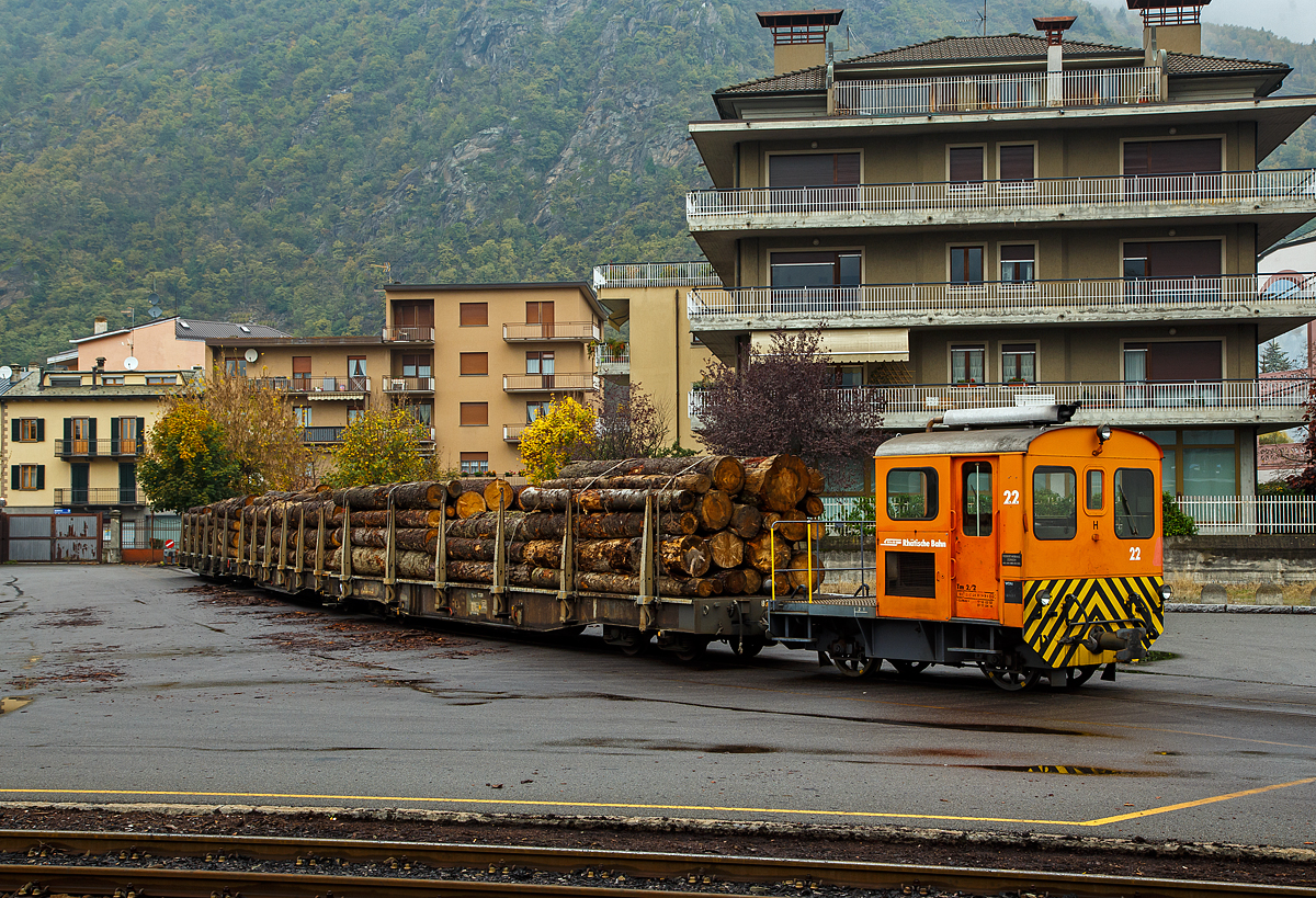 Die RhB Tm 2/2 22, ex RhB Tm 2/2 58, steht am 02.11.2019 mit drei angehangenen und mit Rundholz beladenen Flachwagen vom Typ “Sp-w“ der Serie 8271 – 8300 beim Bahnhof Tirano. 

Der Traktor vom Typ RACO 55 LA 4 wurde 1965 von RACO (Robert Aebi AG) unter der Fabriknummer 1717 gebaut. Im Jahr 1989 erfolgte die Remotorisierung mit einem Cummins Motor vom Typ 4BT 3.9 und die Umzeichnung in Tm 2/2 22.

Als Tm 2/2 werden diesel- oder benzinbetriebene Traktoren (Kleinlokomotiven) bezeichnet.
Die RhB besa im Laufe der Jahre insgesamt 42 zweiachsige Traktoren mit Verbrennungsmotoren. Davon haben sechs eine Funkfernsteuerung und tragen deshalb die Bezeichnung Tmf 2/2. Die verbleibenden 36 Fahrzeuge teilen sich auf in 26 heute orange Rangierfahrzeuge und 10 heute gelbe Baudiensttraktoren. Insgesamt hatte die RhB 12 dieser baugleichen RACO 55 LA 4.

Zwischen 1957 und 1969 lieferte die Firma Robert Aebi (Raco) die dieselmechanischen Traktoren Tm 2/2 64–67, 62–63, 57–61 und schlielich noch Nummer 56. Die Nummerierung erfolgte vor den schon vorhandenen Tm 68 und 69. Basis fr diese Fahrzeuge waren die Tm II der SBB. Der mechanische Aufbau wurde von RACO entwickelt und gebaut, der Dieselmotor war von Saurer-SLM. Die Kraftbertragung vom Motor auf die Achsen erfolgte mittels Kettenantrieb, dadurch sind diese Traktoren nur fr den leichten Verschubdienst an Bahnhfen geeignet. Bei einem Umbau in den Jahren 1989-90 wurden die Motoren von SLM durch solche von Cummins ausgetauscht, dabei wurden die Nummern auf 15 bis 26 gendert und die Traktoren dabei in die Ablieferungsreihenfolge gebracht. Die ursprnglich rotbraun, heute orange lackierten Fahrzeuge sind 5,06 m lang und 9 t schwer. Sie bestreiten den Rangierdienst auf Stationen mit kleinem bis mittlerem Gteraufkommen, wobei die meisten der 12 Traktoren ihrer jeweiligen Heimatstation fest zugeteilt sind.

TECHNISCHE DATEN:
Spurweite: 1.000 mm
Achsfolge: B
Lnge ber Puffer: 5.060 mm
Breite: 2.640 mm
Leergewicht: 9 t
Ladegewicht: 2 t
Hchstgeschwindigkeit: 30 km/h (55 km/h Schleppfahrt)
Motorbauart: 4-Zylinder-Dieselmotor
Motortyp: ab 1989/90 Cummins 4BT 3.9 (ursprnglich Saurer-SLM 4 VD 11)
Motorleistung: 62 kW (ursprnglich 44 kW)
Anfahrzugkraft: 30 kN (ursprnglich 25 kN)
Stundenzugkraft: 15 kN bei 10 km/h
Leistungsbertragung: Rollenkette

Die offenen, vierachsigen RhB Flachwagen mit Rungen vom Typ Sp-w der Serie 8271 – 8300 sind die Allrounder der Rhtischen Bahn schlechthin und werden vorwiegend fr den Transport von Rundholz eingesetzt. An jeder Lngsseite besitzen sie sechs Steckrungen.

TECHNISCHE DATEN vom Typ Sp-w (8271 bis 8300) :
Typenbezeichnung:  Sp-w
Wagennummern:  8271 bis 8300
Baujahr: 1979
Spurweite: 1.000 mm
Lnge ber Puffer: 16.540 mm 
Drehzapfenabstand: 11.000 mm 
Achsabstand im Drehgestell: 1.400 mm
Laufraddurchmesser: 750 mm (neu)
Breite ber Alles: 2.700 mm
Ladelnge: 15.500 mm
Ladebreite:  2.310 mm
Rungenhhe: 1.050 mm
Ladeflche: 34 m
Eigengewicht:  ca. 15.600 kg
Ladegewicht:  33 Tonnen
Hhe ab Schienenoberkante: 965 mm