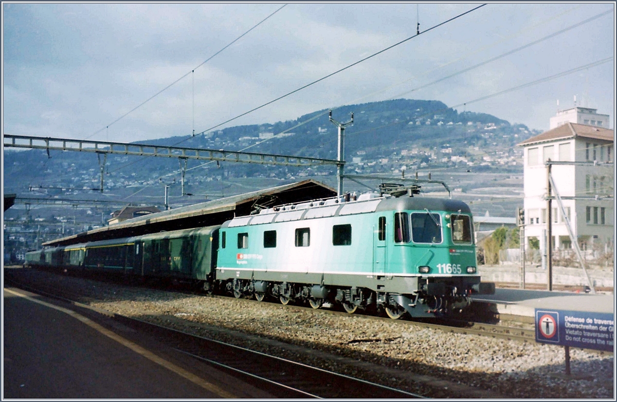 Die SBB Re 6/6 11655 in der gefälligen, aber dann verworfen Cargo Lackierung mit einem Schnellzug nach Brig beim Halt in Vevey. 

Das Bild entstand im Frühling des Jahres 2000 in Vevey. 

