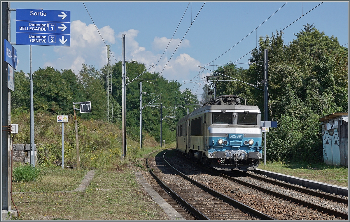 Die SNCF BB 22391 ist mit ihrem TER 96564 von Genève nach Lyon unterwegs und fährt durch den Bahnhof von Pougny-Chancy. Interessant sind links im Bild die Hinweisschilder, in Pougny-Chancy gibt es statt wie sonst oft in Frankeich üblich kein Gleise  A  und  B , sondern den Bahnstieg 1 und 2, zudem sind die Pfeile ernst zu nehmen, von einen Bahnsteig zu andern andern oder zum Ausgang muss man die Gleise überqueren, der Übergang ist vom Fotostandpunkt aus hinter meinem Rücken rechts und folglich nicht zu sehen. Bei einer nahenden Zugsdurchfahrt warnen rote Lampen. 6. Sept. 2021