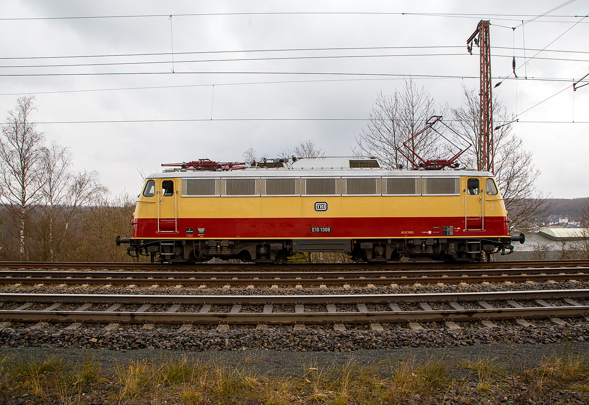 Die TRI E10 1309 (91 80 6113 309-9 D-TRAIN) der Train Rental International GmbH hat am 18.03.2021 als Lokzug in Rudersdorf (Kr. Siegen), an der Dillstrecke (KBS 445), Hp 0. Sie muss erst einen Güterzug überholen lassen.

Die Lok, eine sogenannte „Bügelfalten“ E10.12 mit Henschel-Schnellfahrdrehgestellen für dem TEE Rheingold bzw. TEE Rheinpfeil, wurde 1963 von Krauss-Maffei in München-Allach unter der Fabriknummer 19014 gebaut (der elektrische Teil ist von Siemens) und an die Deutschen Bundesbahn als E10 1309 geliefert. Mit der Einführung des EDV-gerechte Nummernsystems erfolgte zum 01.01.1968 die Umzeichnung in DB 112 309-0. Nach der deutschen Wiedervereinigung und dem darauffolgenden Vereinigung der beiden deutschen Staatsbahnen (DB und DR) wurde sie zum 01.01.1991 in DB 113 309-9 umgezeichnet und fuhr so bis zur Ausmusterung und Verkauf im Jahr 2014.

TECHNISCHE DATEN:
Spurweite: 1.435 mm
Achsformel: Bo’Bo’
Länge über Puffer: 16.440 mm
Drehzapfenabstand:  7.900 mm
Achsabstand im Drehgestell:  3.400 mm
Dienstgewicht: 85,0 t
Höchstgeschwindigkeit: 160 (zeitweise 120 km/h)
Stundenleistung: 3.700 kW (kurzzeitig bis 6.000 kW)
Dauerleistung: 3.620 kW
Anfahrzugkraft: 275 kN
Treibraddurchmesser: 1.250 mm
Stromsystem:  15 kV 16 ⅔ Hz ~
Anzahl der Fahrmotoren: 4
Antrieb: Gummiringfeder
Bremse: mehrlösige Knorr-Einheits-Druckluftbremse, Zusatzbremse, fremderregte elektrische Widerstandsbremse (max. Bremsleistung 2.000 kW, Dauerleistung 1.200 kW)