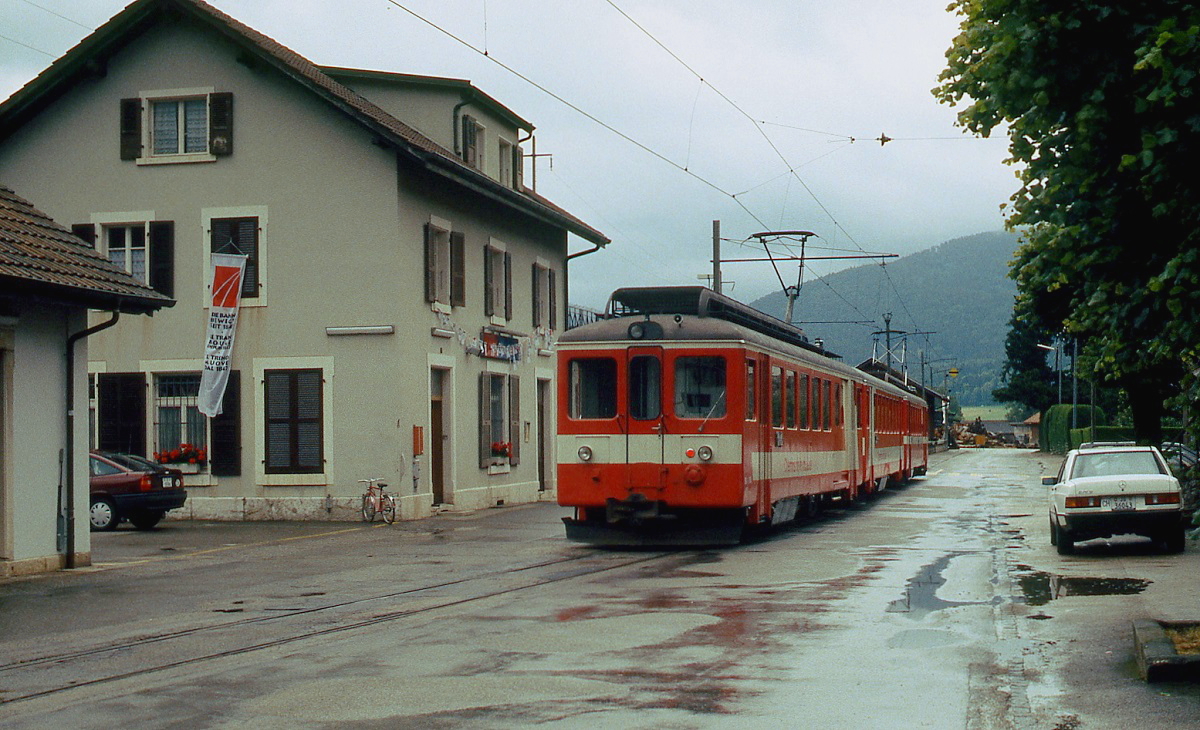 Direkt vor dem Bahnhofsgebäude von Glovelier warten zwei BDe 4/4 der CJ im Sommer 1991 auf Fahrgäste