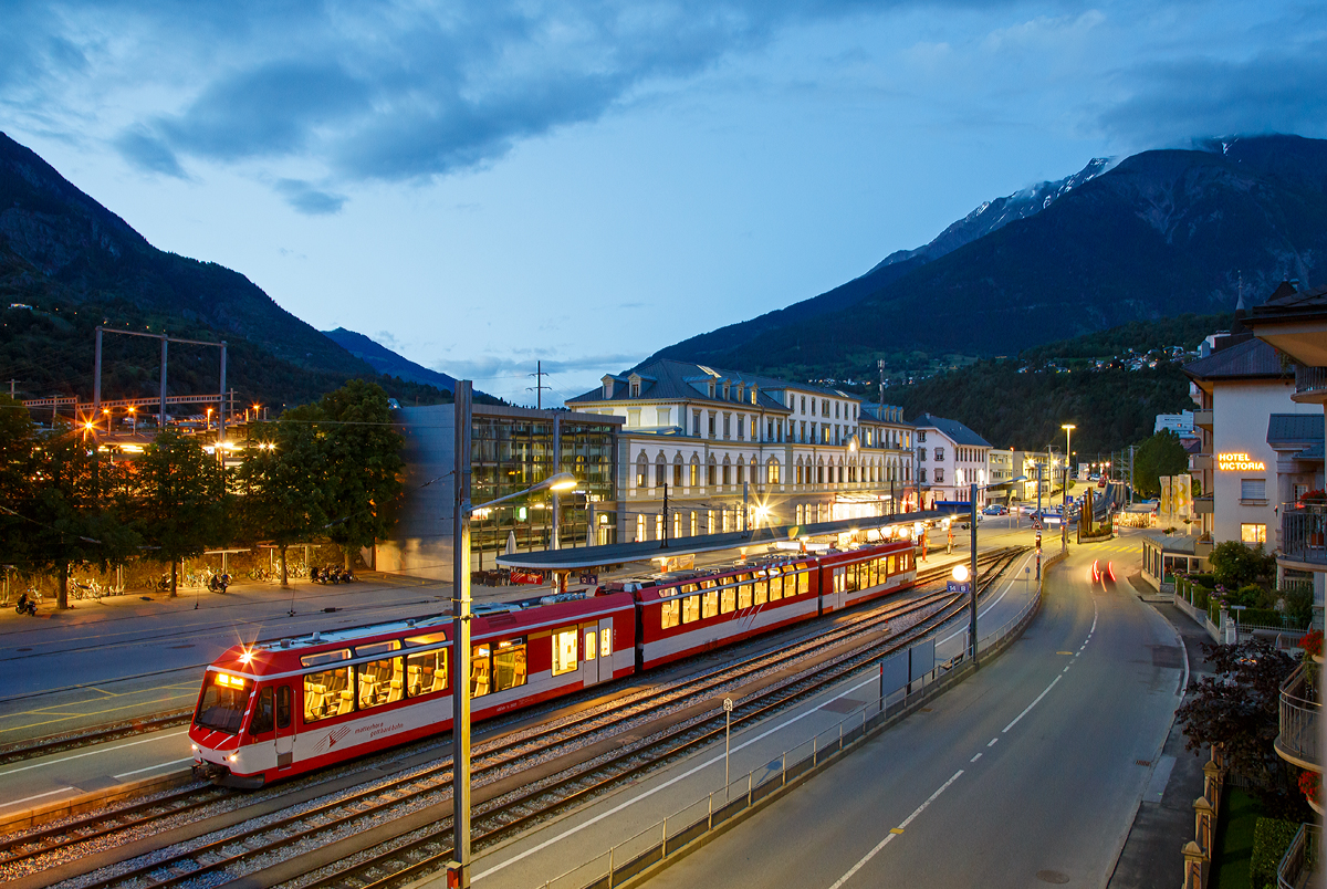 Ein abendlicher Blick vom Balkon des Hotels Europe in Brig am 19.06.2016, auf den Bahnhof Brig. Vorne der Bahnhofvorplatz mit den Gleisen und Bahnsteigen der MGB, wo gerade der  KOMET  ABDeh 4/8 - 2022 als RB nach Zermat hlt. Hinten das Empfangsgebude vom SBB Bahnhof.