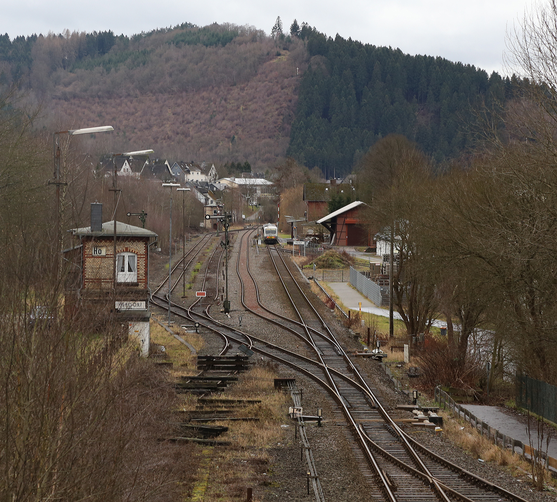 
Ein Blick am 09.01.2014 von der Brücke Wolfsweg ( Achenbachs Brücke ) auf den Bahnhof Herdorf, wo gerade der Dieseltriebwagen VT/VS 51 (BR 628.4) der Westerwaldbahn als RB 96  Hellertal Bahn  (Neunkirchen-Herdorf-Betzdorf) hält. 
Gut zu sehen sind auch die beiden Stellwerke, vorne links das Wärterstellwerk Herdorf Ost (Ho) und im Hintergrund das Fahrdienstleiterstellwerk Herdorf (Hf).
