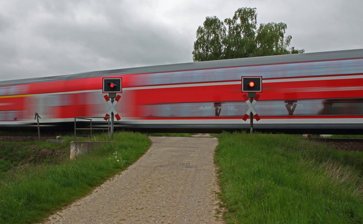 Ein Doppelstockzug von Mühldorf nach München passiert am 03.05.14 gerade einen Bü am Rande Markt Schwabens. Wenige Meter später beginnt der Fahrdraht.