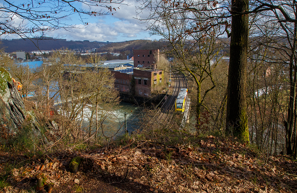 Ein LINT 48 der HLB (Hessische Landesbahn) hat am 26.02.2022 den 32 m kurzen Mühlburg-Tunnel durchfahren, überquert nun die Sieg und erreicht bald den Bahnhof Scheuerfeld (Sieg). Er fährt als RB 90  Westerwald-Sieg-Bahn  die Verbindung Westerburg - Altenkirchen - Au/Sieg - Betzdorf – Siegen.

Heute war die Siegstrecke zwischen Scheuerfeld (Sieg) und Niederhövels nur eingleisig befahrbar. Den Grund sieht man link im Bild, zwei Kletterer sind in der Felswand und führen eine Felsberäumung durch. Dabei werden alle losen Steine entfernt, um die Gefahr eines möglichen Steinschlages zu mindern.

Unten beim Wehr RWE Scheuerfeld einem Laufwasserkraftwerk, sieht am die Sieg toben. Dahinter die ehemalige Papierfabrik.
