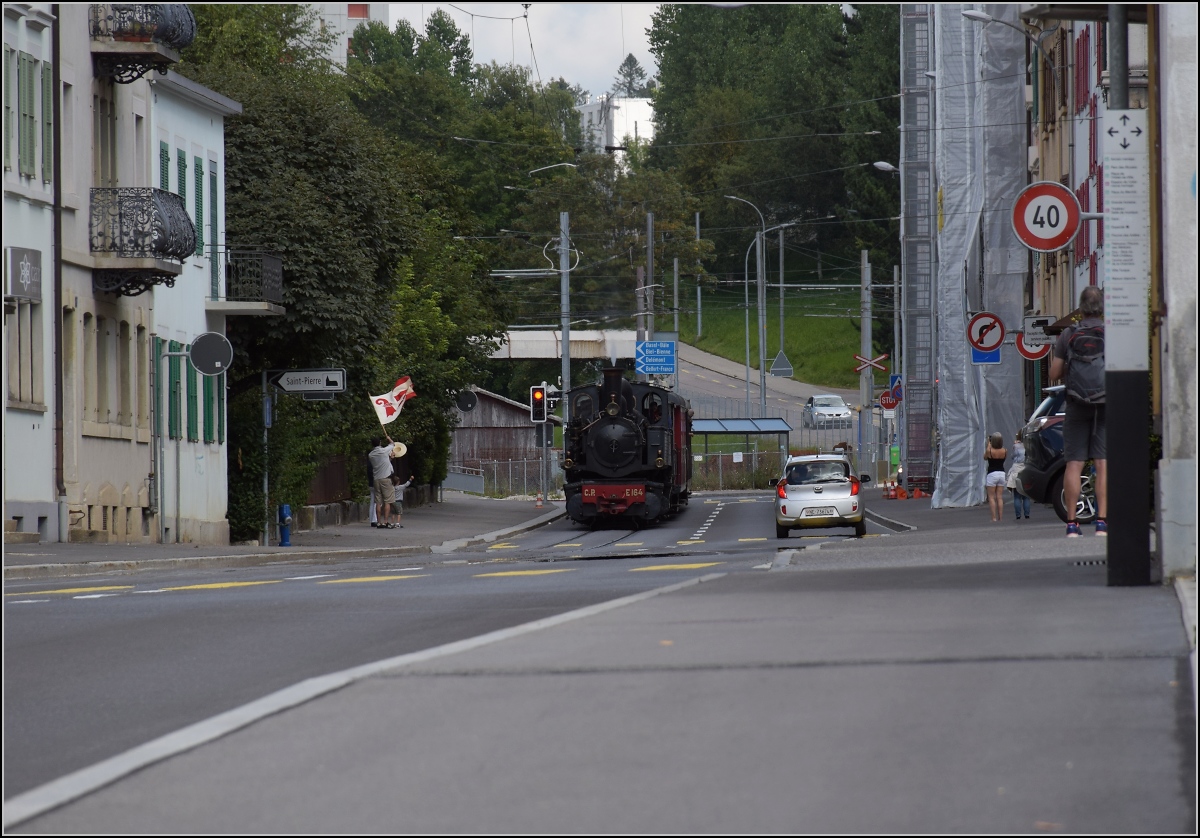 Eine etwas ungewöhnliche Verkehrsteilnehmerin in La Chaux-de-Fonds. 

CP E 164, heute bei La Traction, hat ihren jährlichen Einsatz auf der Strasse und wird von einem Fahnenschwinger mit der jurassischen Fahne im Kanton Neuenburg begrüsst. September 2021.