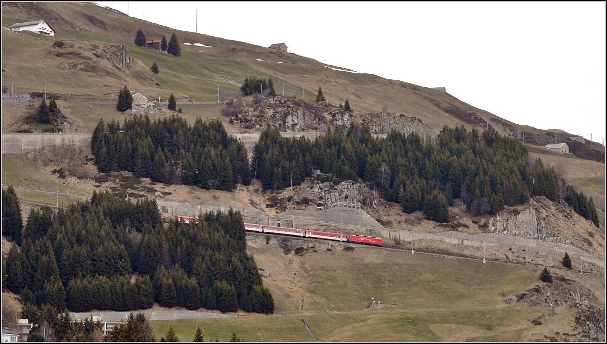 Eine HGe 4/4<sup>II</sup> mit Regionalzug steigt vom Oberalppass die Kehren am Hang von Nätschen nach Andermatt herab. April 2016.