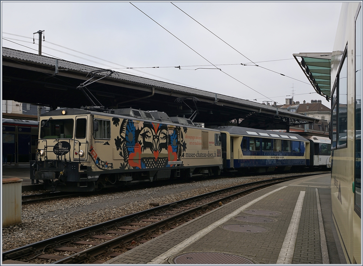 Eine MOB GDe 4/4 wartet in Montreux mit ihrem Panoramic Express auf die Abfahrt nach Zweisimmen. Das interessante dieses bildes ist der in Origainal-Farben zurückversetze ertse Wagen anlässlich des Jubiläums  40 Jahre-Panoram-Wagen .
14. Dez. 2016