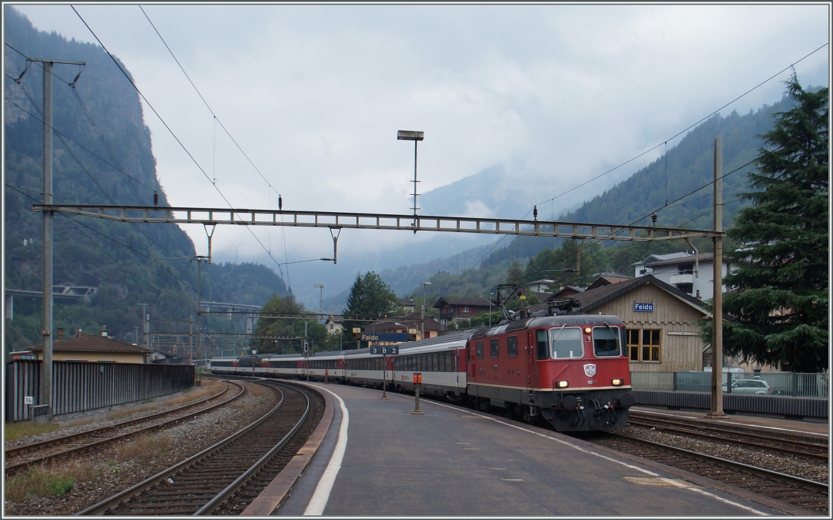 Eine Re 4/4 II erreicht mit ihrem IR 2421 von Zürich nach Locarno den Bahnhof Faido.
22. Sept. 2015 