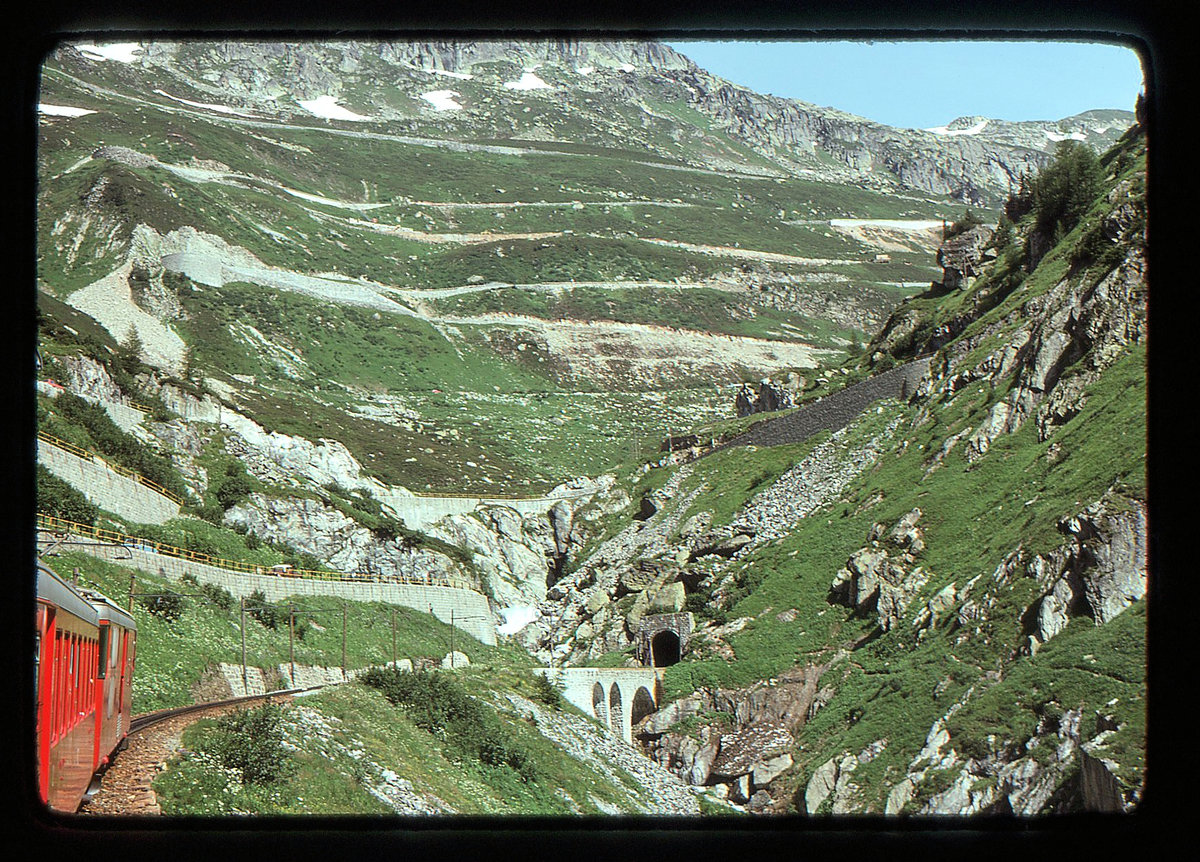 Furka Bergstrecke zur Zeit des elektrischen Betriebs: Unterhalb des Kehrtunnels im Aufstieg von Oberwald nach Gletsch, mit Blick auf die Grimsel-Passstrasse. 28.Juli 1975 