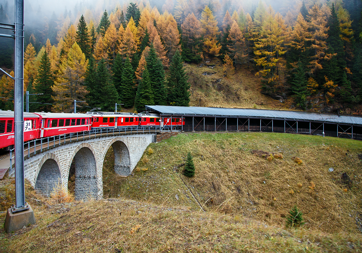 Geführt von den beiden RhB ABe 4/4 III Triebwagen Nr. 54  Hakone  und 53  Tirano  fährt am 02.11.2019 unser RhB Regionalzug nach Tirano von Alp Grüm in Richtung Cavaglia hinab, hier geht es (bei km 31,75) erst über das 32 m lange Aqua da Pila Viadukt und dann durch die 88 m lange Viadotto Pila Galerie. Hier auf ca. 1.777 m ü.NN gint es z.Z. keinen Schnee aber der Nebel ist noch da.