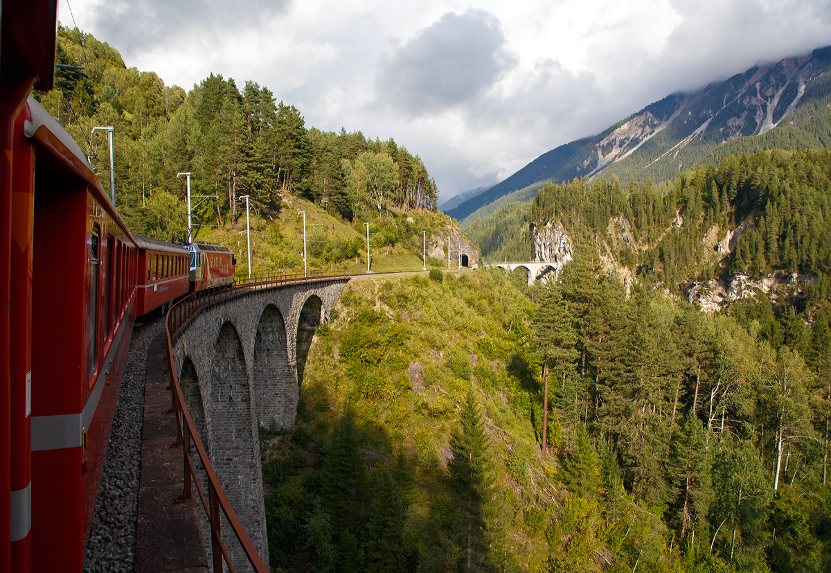 
Gezogen von der RhB Ge 4/4 III 651  Fideris  fährt unser IR-Zug am 12.09.2017 auf der Albulalinie in Richtung St. Moritz. Hier befinden wir uns gerade auf dem Schmittentobel-Viadukt (35 m hoch, 137 m lang), danach folgt der 27 m lange Zalaint-Tunnel und das Lehnenviadukt (nicht im Bild), bevor es dann über das berühmte Landwasserviadukt und gleich anschließenden durch den 216 m langen Landwasser-Tunnel geht.