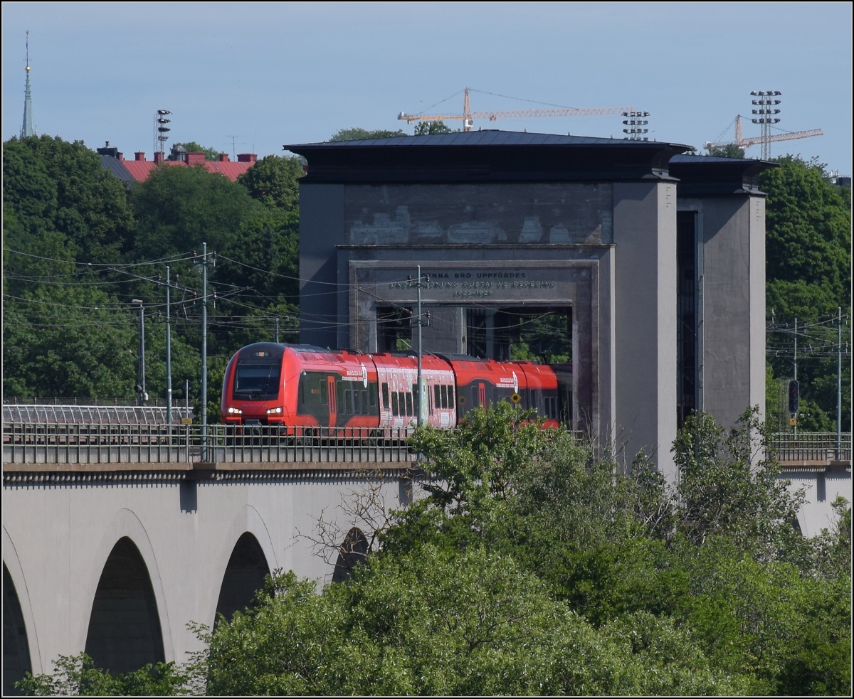 Hochgeschwindigkeits-Flirt in Schweden. 

X74 005 'Glenn' der MTR auf der Årstabrücke. Das anhebbare Segment erscheint wie ein Tor zum Stockholmer Stadtteil Södermalm. Årstaberg, Juni 2018.