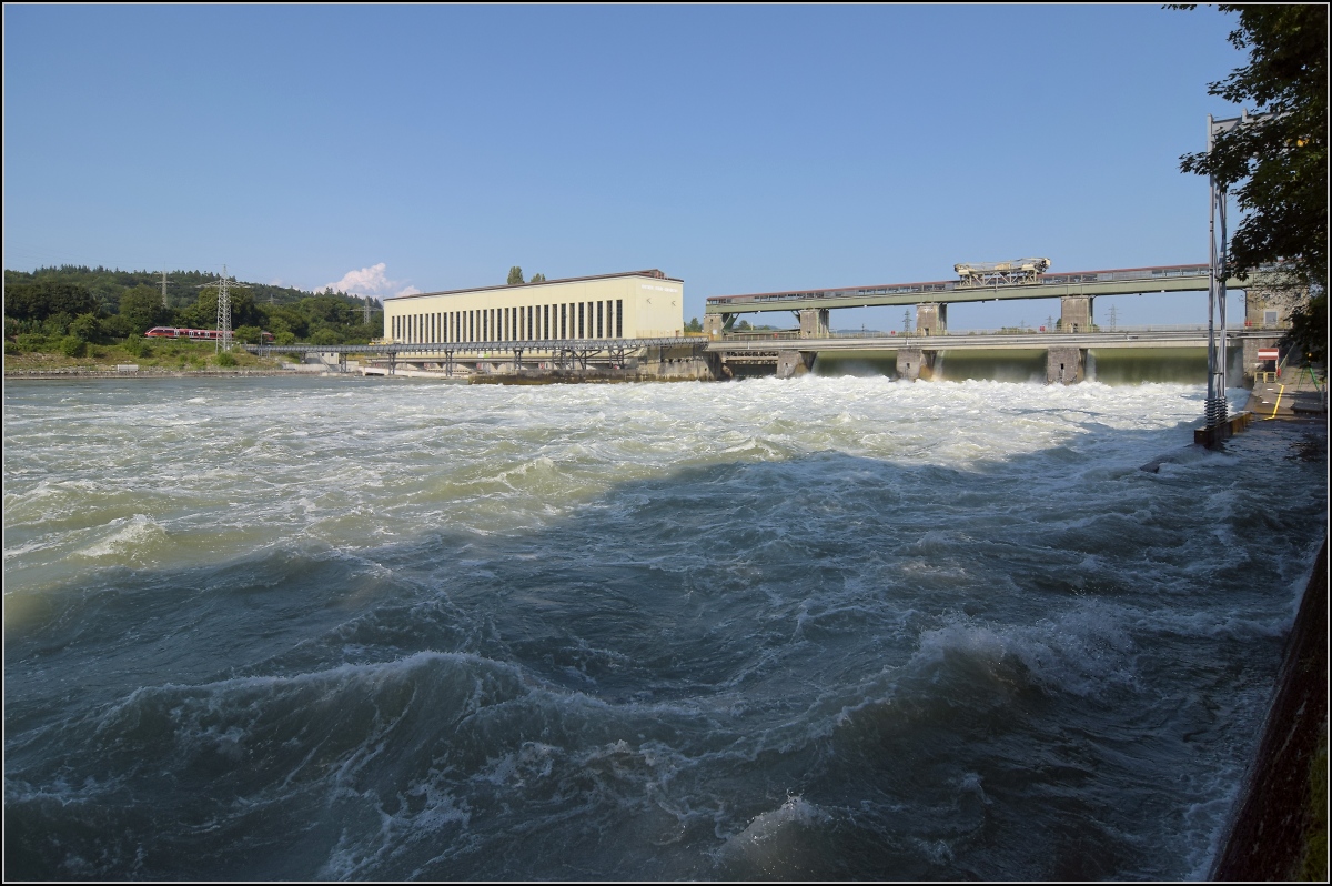 Hochwasser am Hochrhein.

Durch die Flutwehre des Kraftwerk Ryburg-Schwörstadt rauscht mehr Wasser am Kraftwerk vorbei (dürfte ca. 1000 m²/s sein), als am Rheinfall zur gleichen Zeit herunterstürzt. Entsprechend laut ist das Getöse. Trotzdem hört man auch den 644 auf der deutschen Seite ganz deutlich. Möhlin, Juli 2021. 