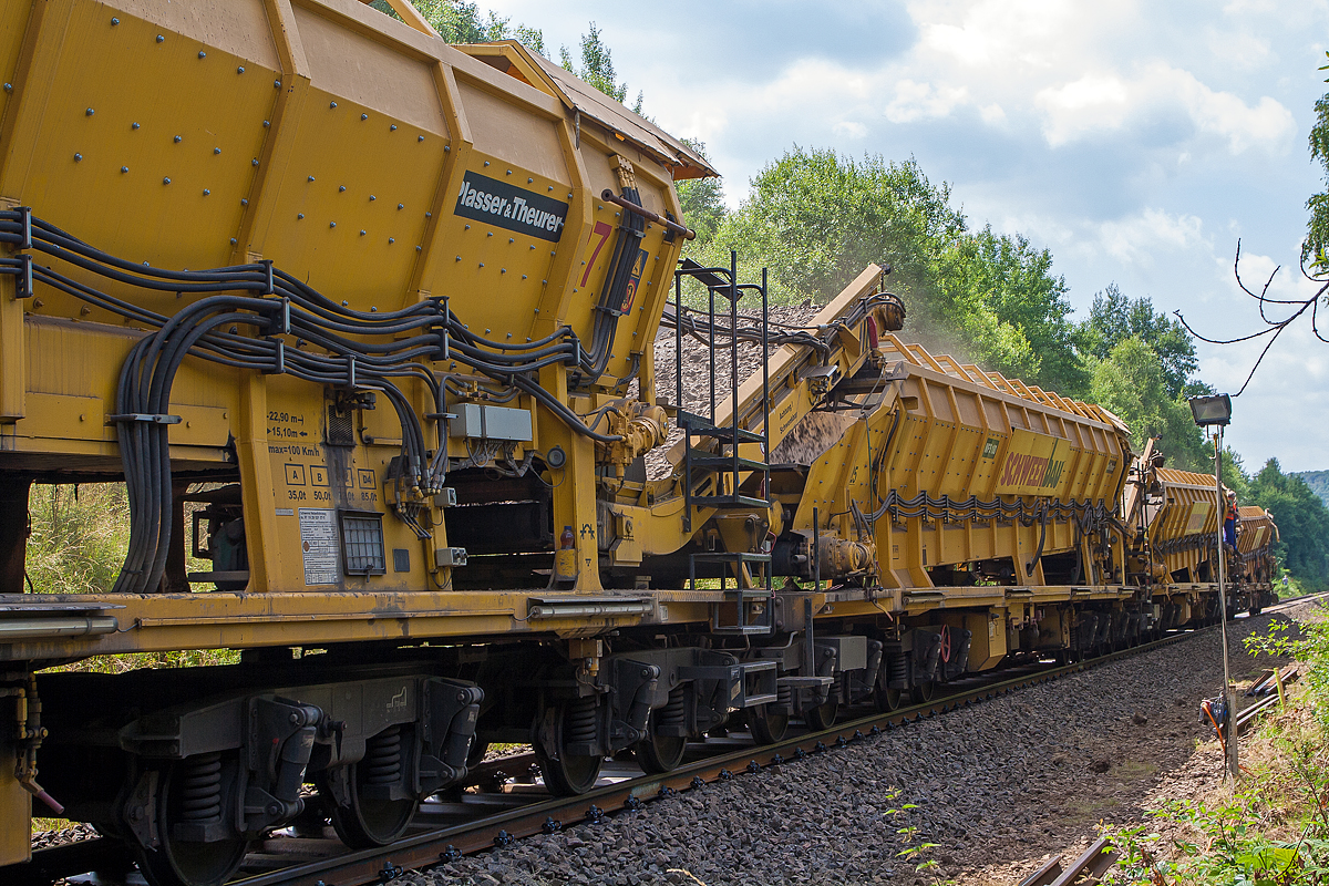 Im Einsatz auf der Hellertalbahn (KBS 462) bei Würgendorf am 15.07.2013: Die Plasser & Theurer Hochleistungs-Bettungsreinigungsmaschine RM 95-800 W, Schweres Nebenfahrzeug Nr. 99 80 9414 001-4 D-MWGB, der MGW Gleis- und Weichenbau-Gesellschaft mbH & Co. KG (Berlin). 

Detailbild Abraum:
Die Maschine schiebt vier Materialförder- und Siloeinheiten MFS 100 der Schweerbau, in diese wird der Abraum (Altschotter) befördert. Weitere nun geleerte MFS 100 werden von einer Lok wieder heran geschoben und gleich wieder angekuppelt. Wenn diese angekuppelt sind, werden die vier, vor der Maschine befindlichen, gefüllten MFS 100 in diese wieder entleert.