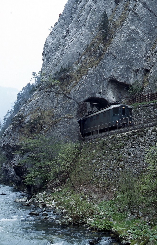 Im Juli 1983 fährt eine Re 4/4 I durch die Klus zwischen Choindez und Moutier. An den engsten Stellen dieser Schlucht reicht der Platz gerade für Straße und Fluß aus, die Bahn muß dagegen den Weg durch Tunnel und Felsdurchstiche nehmen. 