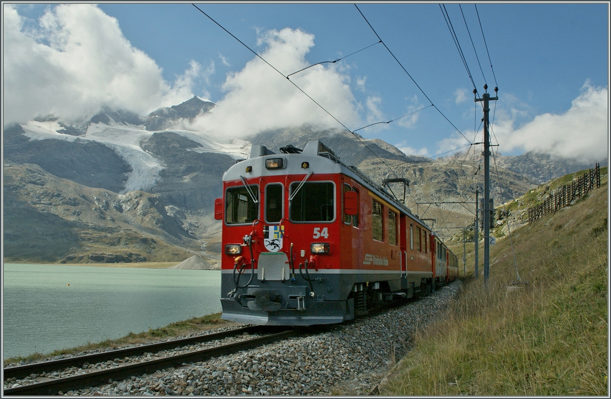 Im Schatten einer Wolke fahrt der Bernina ABe 4/4 N 53 mit einem Schwestertriewagen  und einem langen Regionalzug nach Tirano am Lac Bianco entlang und erreicht in Krze Ospizio Bernina. 
10. Sept. 2011