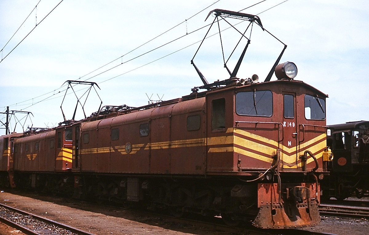In den 1920er Jahren wurde als erste südafrikanische Strecke die Verbindung von Durban über Pietermaritzburg nach Glencoe elektrifiziert. Zwischen 1925 und 1945 wurden in 7 Serien insgesamt 172 Lokomotiven der Class 1E von verschiedenen Herstellern (Metropolitan-Vickers, SLM, Robert Stephenson & Hawthorns, Werkspoor) an die South African Railways geliefert. Die 1. (1923/24, 60 Stück) und 5. Serie (1938, 22 Stück) stammen von SLM. Zu letzterer gehört auch die abgebildete E 149, die im November 1976 in Pietermaritzburg aufgenommen wurde.