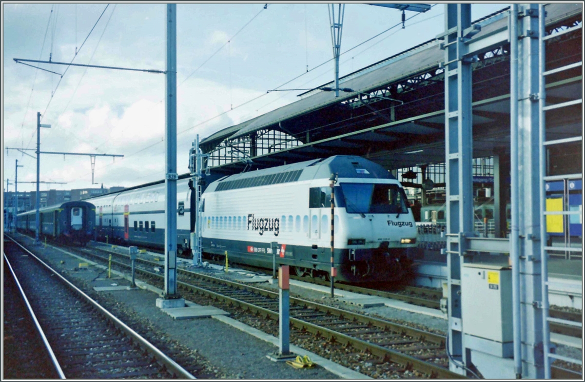 In Basel SBB wirbt zwischen vielen Masten die Re 460 112-6 für den  Flugzug  Basel SBB - Zürich Flughafen. Die Lok ist mit einen Doppelstockzug bespannt, ansonsten dominieren noch die EW I/II.

Analogbild vom 31. Jan 2001  