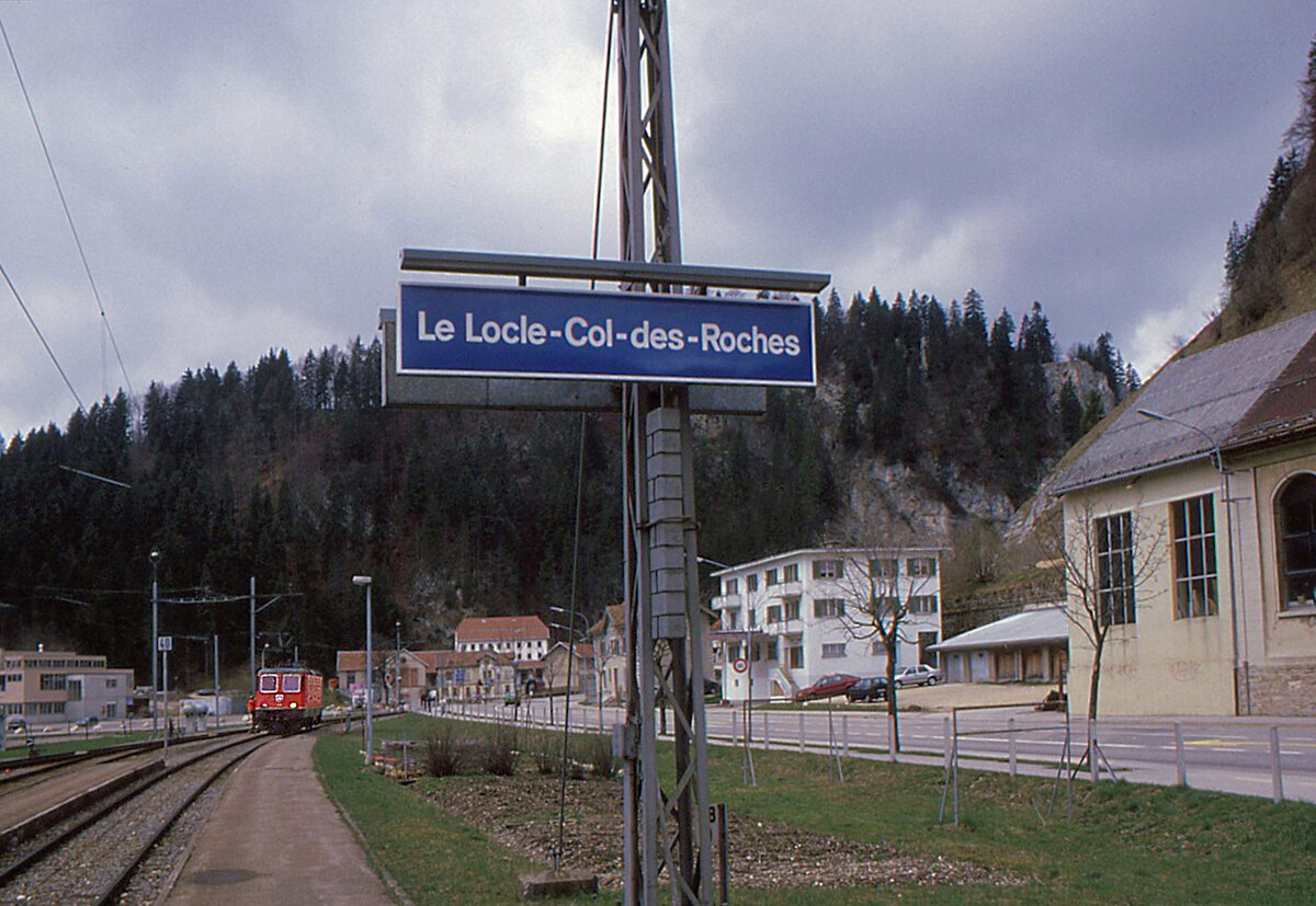 Le Locle - Le Locle-Col-des-Roches: Mit dem Rangierarbeiter an der Lok  hängend  zieht Re 4/4 II 11249 vor, um ihren Zug zu umfahren. Im Hintergrund die schweizerisch/französische Grenze. 20.April 1995 