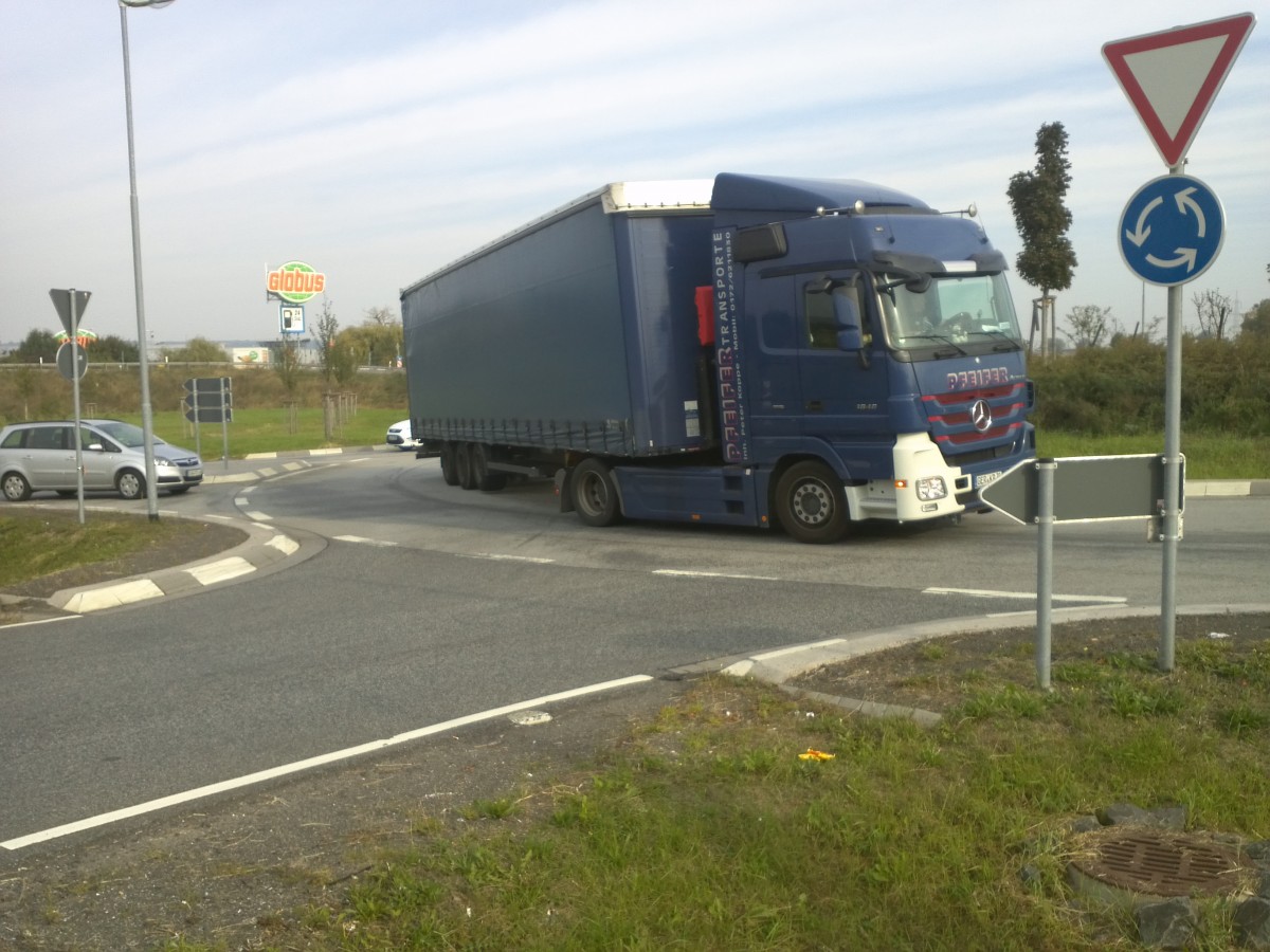 LKW SZM Mercedes-Benz Actros mit Pritsche-Planen-Auflieger der Spedition Pfeifer
Transporte im Kreisel vor dem Autohof in Grnstadt am 01.10.2013