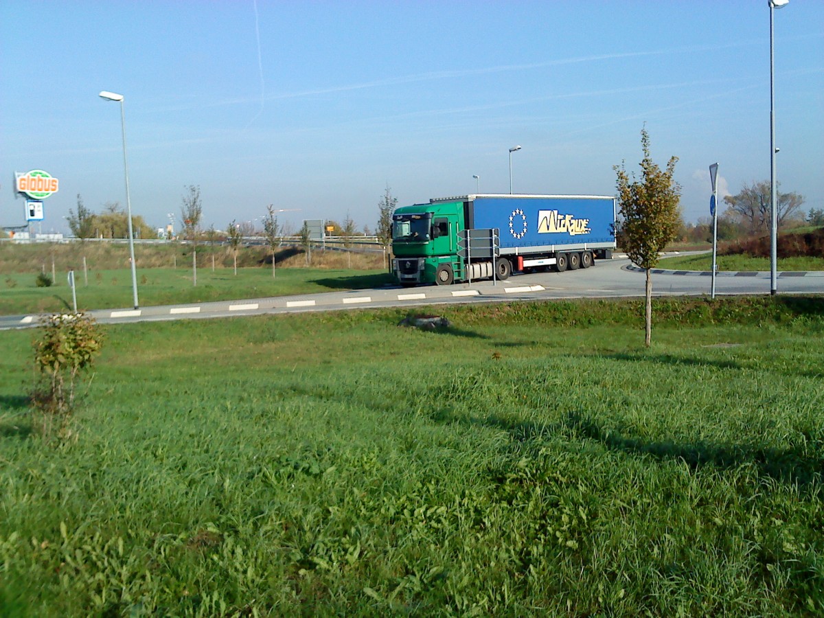 LKW SZM Renault Magnum mit Pritsche-Planen-Auflieger im Kreisel vor dem Autohof in Grnstadt am 31.10.2013