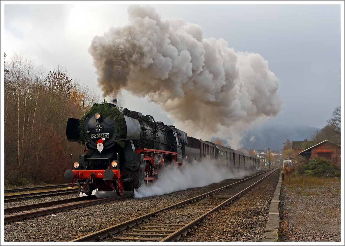 
Mit mächtiger Rauchfahne durchfährt die Betzdorfer 52 8134-0 am 01.12.2013 Herdorf, hier kurz hinter dem Bahnhof. Heute veranstalten die Eisenbahnfreunden Betzdorf ihre alljährlichen Nikolausfahrten zwischen Betzdorf/Sieg und Würgendorf.

 Die Lok war, bedingt durch die Wiedervereinigung, eine der letzten Normalspurigen Dampfloks der DB.  Zudem war sie als 052 134-4 die einzige wahre 52 der DB (BR 52.80). Die Lok wurde 1965 aus der 1943 bei der Lokfabrik Wien-Floridsdorf (Fabriknummer 16591) gebauten 52 7138 rekonstruiert.
