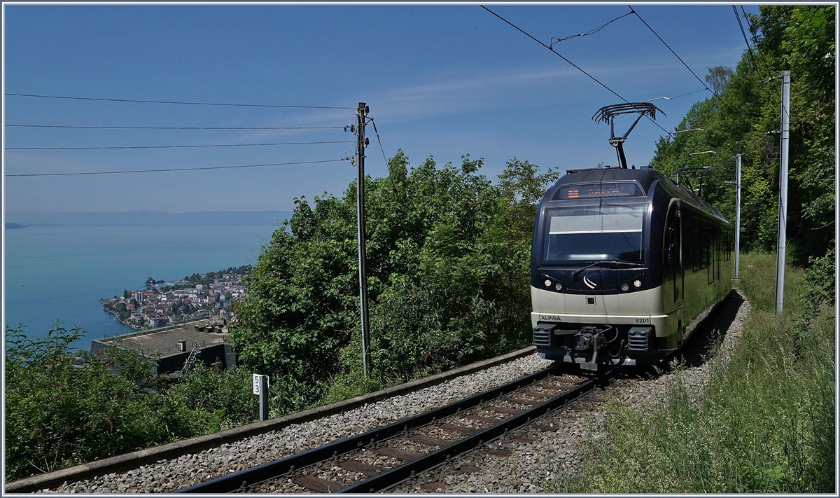 Neben dem Blick auf den nach Montreux fahrenden Be 4/4 9201  Alpina  gleitet der Blick auch über den tief unten liegenden See und die ihn umgebende Landschaft. 
Das Bild entstand bei Sonzier. 

9. Mai 2020