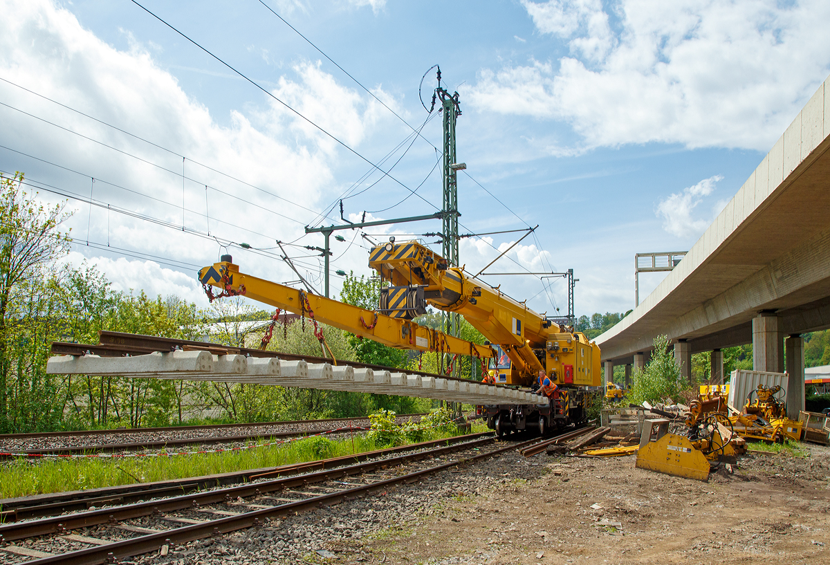 
Nun hat der 125t - KIROW Gleisbauschienenkran KRC 810 T der Hering Bau (Burbach), Schweres Nebenfahrzeug Nr. D-HGUI 99 80 9419 010-0, ein Gleisjoch an der Traverse und fährt am 09.05.2015 wieder Richtung Hauptbahnhof Siegen.

Die zwei Männer auf den Trittflächen müssen das Gleisjoch ruhig halten, damit es sich nicht unkontrolliert dreht oder schwankt.