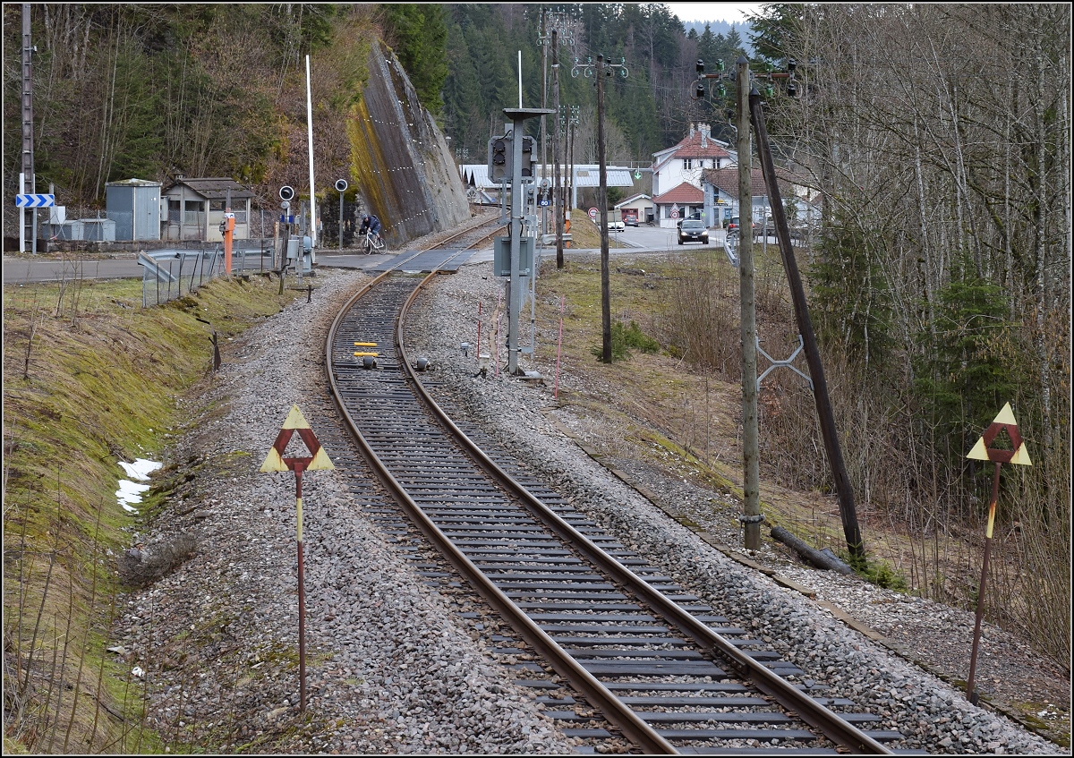 Praktisch bis zum letzten Meter auf französischem Boden ist die Strecke Besançon–Le Locle mit Telegrafenmasten ausgestattet. Erst nach dem Bahnübergang liegt die Zollstation der Strasse mangels Platz fernab der eigentlichen Grenze. Villers-le-Lac, April 2018.